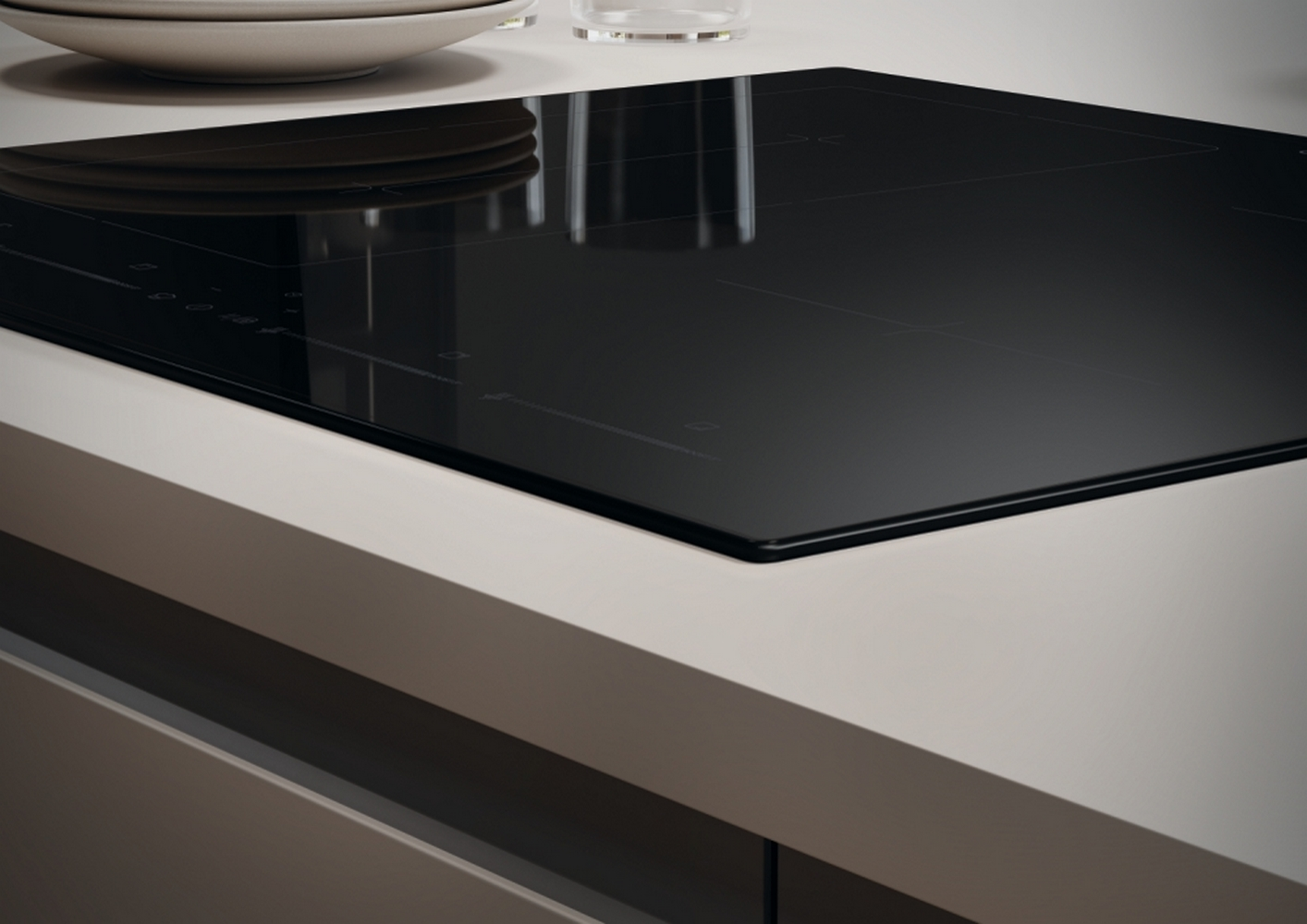 Zbliżenie czarnej płyty indukcyjnej na białym blacie, z białym tłem.