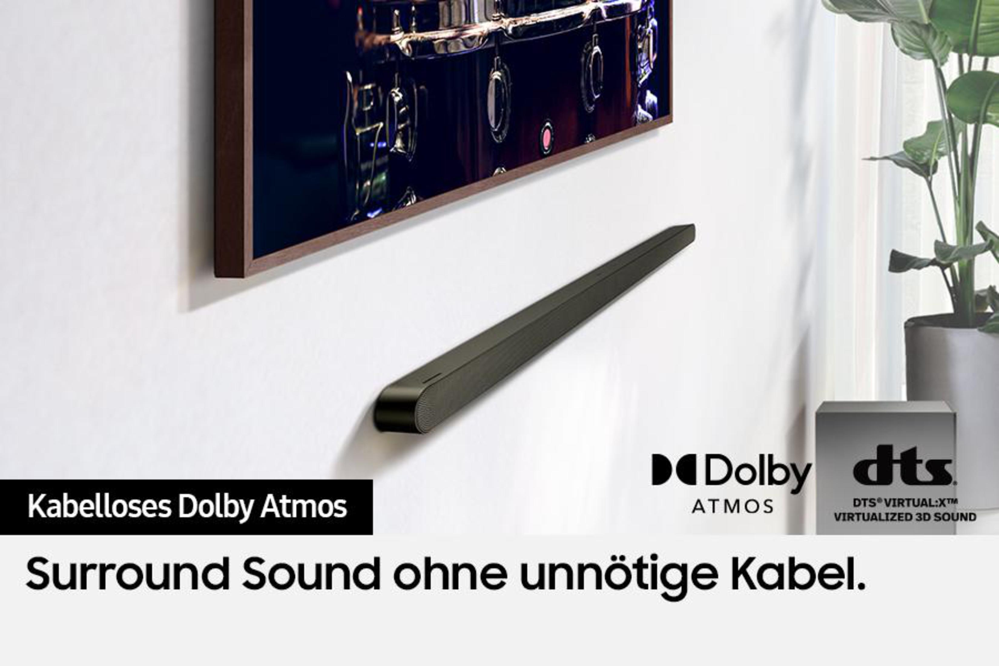 Schwarze Soundbar unter einem Fernseher, Dolby Atmos und DTS Branding an weißer Wand.