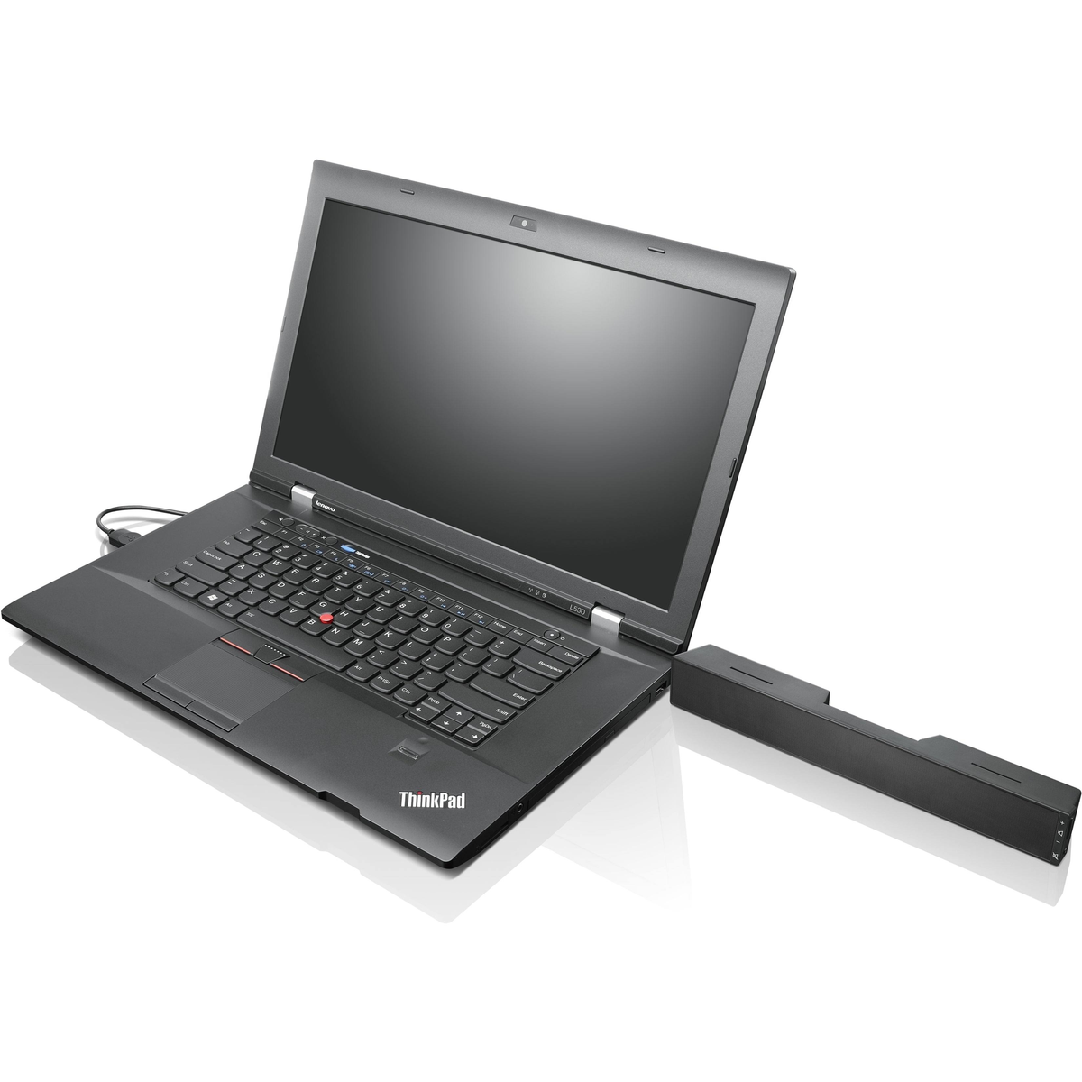 Ordinateur portable ThinkPad noir avec un haut-parleur à côté, sur une surface blanche.