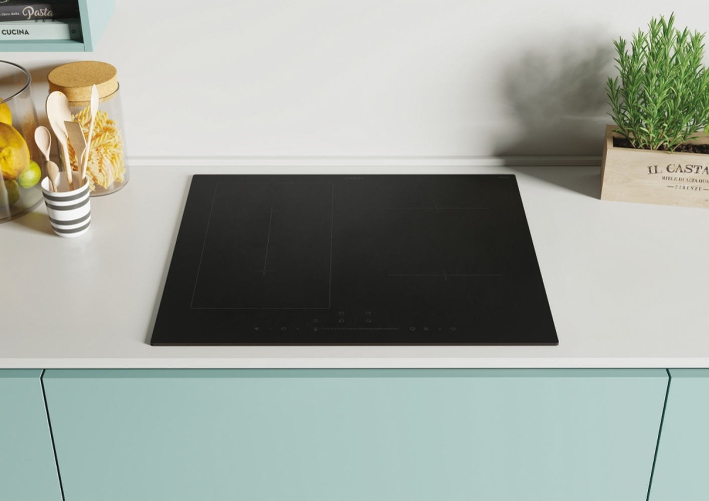 Czarna płyta indukcyjna na miętowym blacie. Słoiki z łyżkami i makaronem po lewej.