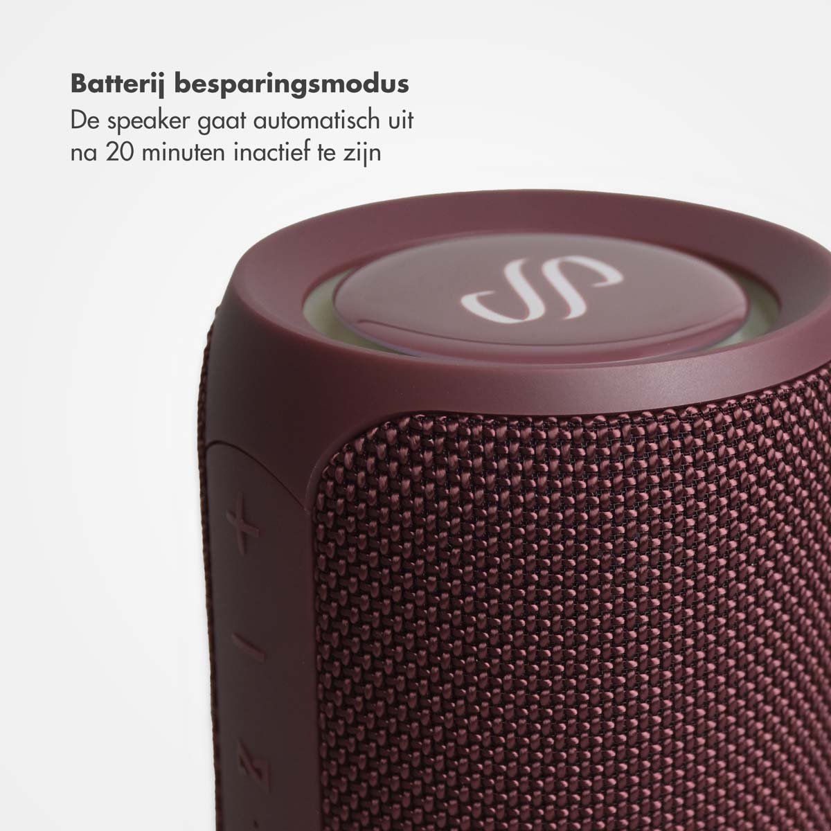 Een close-up van een bordeauxrode luidspreker met een mesh-ontwerp en een logo bovenop.