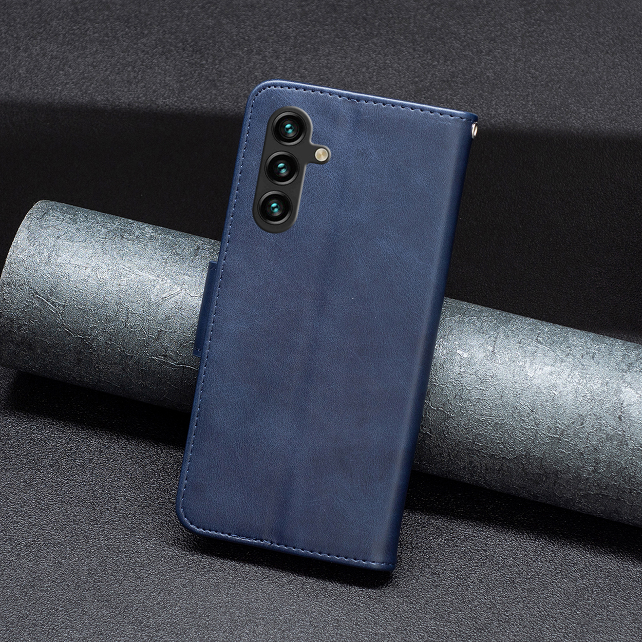 Een blauwe leren telefoonhoes wordt getoond op een donkere achtergrond. Hij heeft drie cameralenzen.