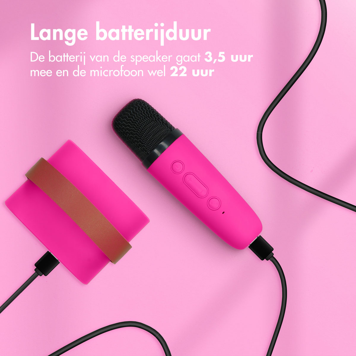 Roze luidspreker en microfoon met een oplaadpad en een zwarte kabel op een roze oppervlak.