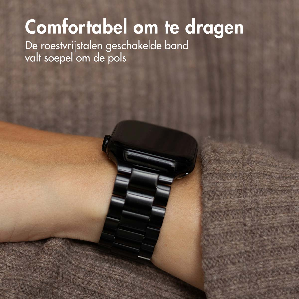 A person wearing a black, metal link watch band on the wrist. The band is flexible.