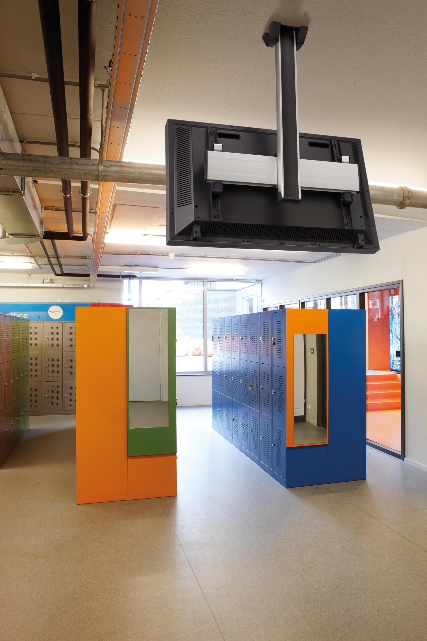 Innenaufnahme von Schließfächern und abgehängtem Fernseher. Orange, blaue Schließfächer.