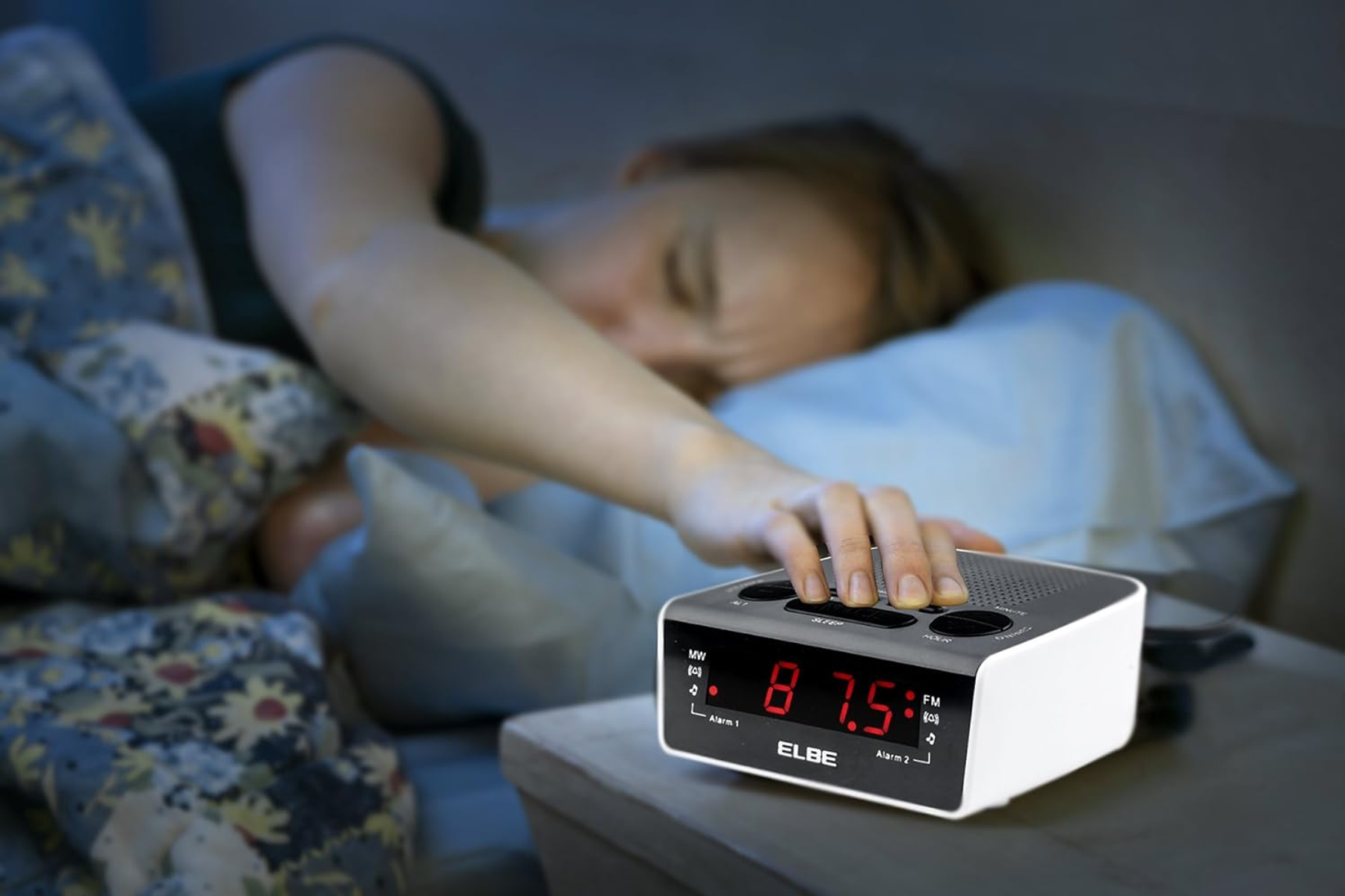 Kobieta sięgająca po wyłączenie budzika ELBE.