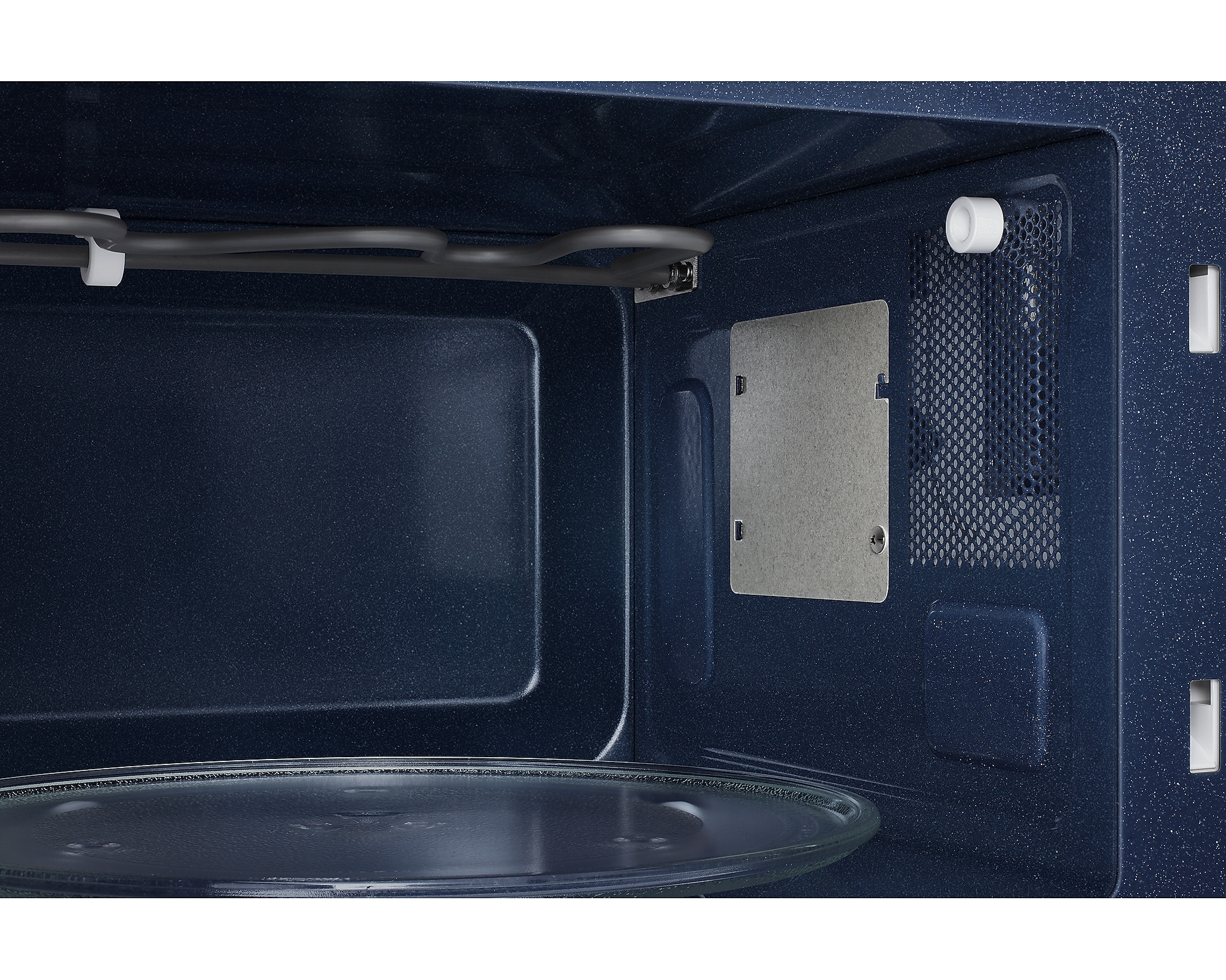 Interno di un microonde. Interno blu scuro, piatto in vetro, elemento riscaldante e ventilazione.