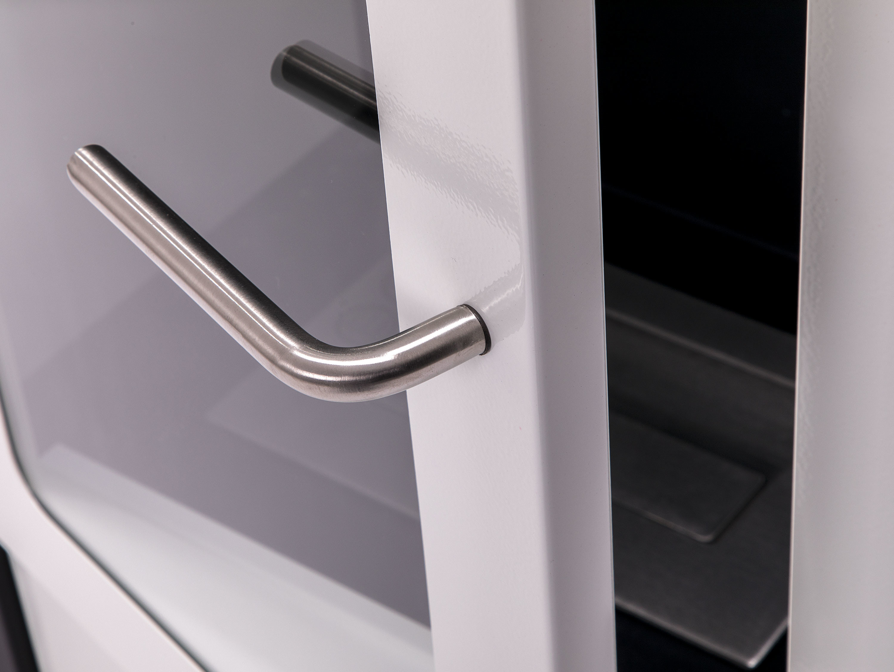 Primer plano de una puerta de armario blanca con un tirador plateado, abierta.