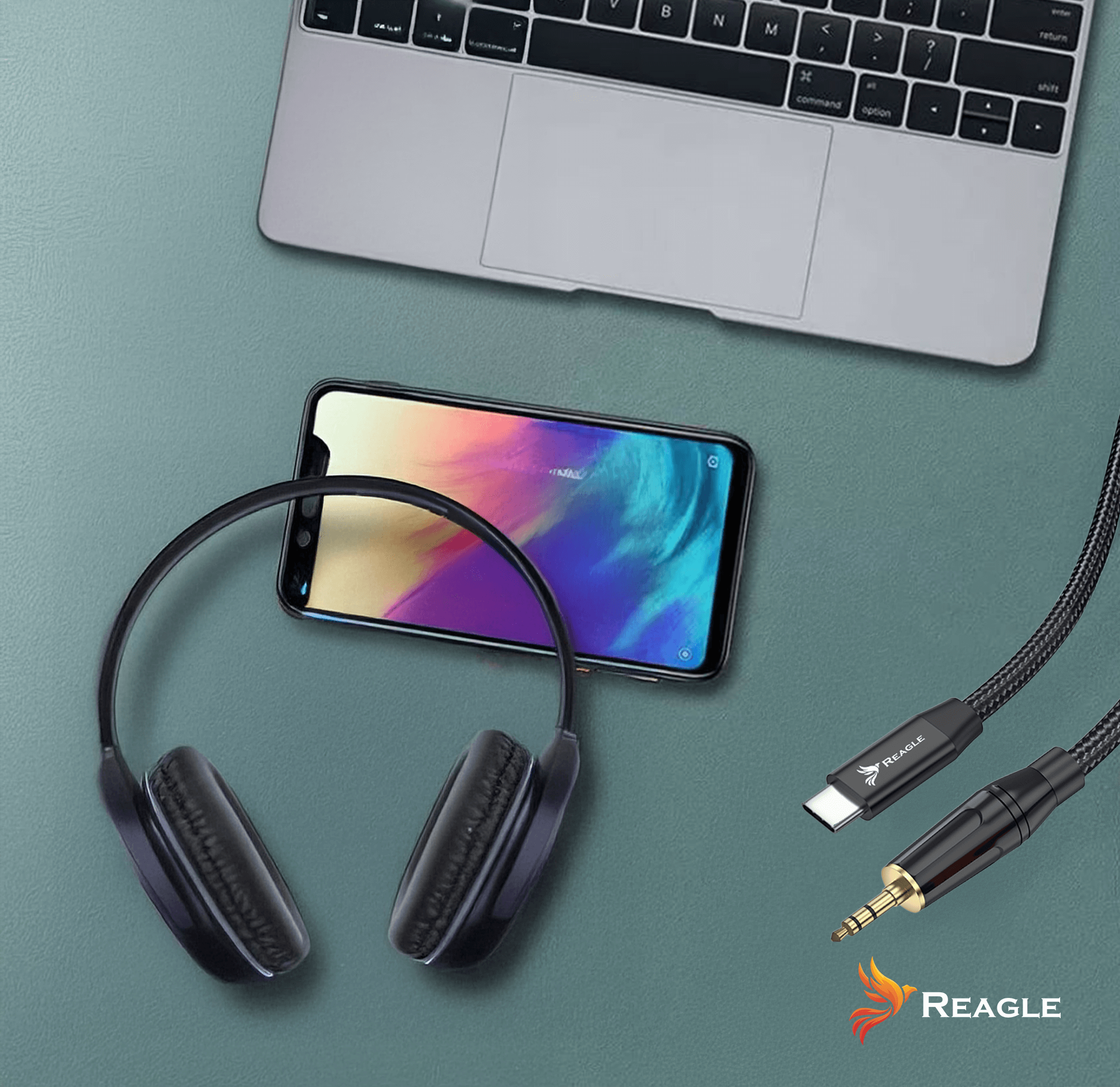 Słuchawki, telefon i kable na zielonej powierzchni. Laptop w tle.