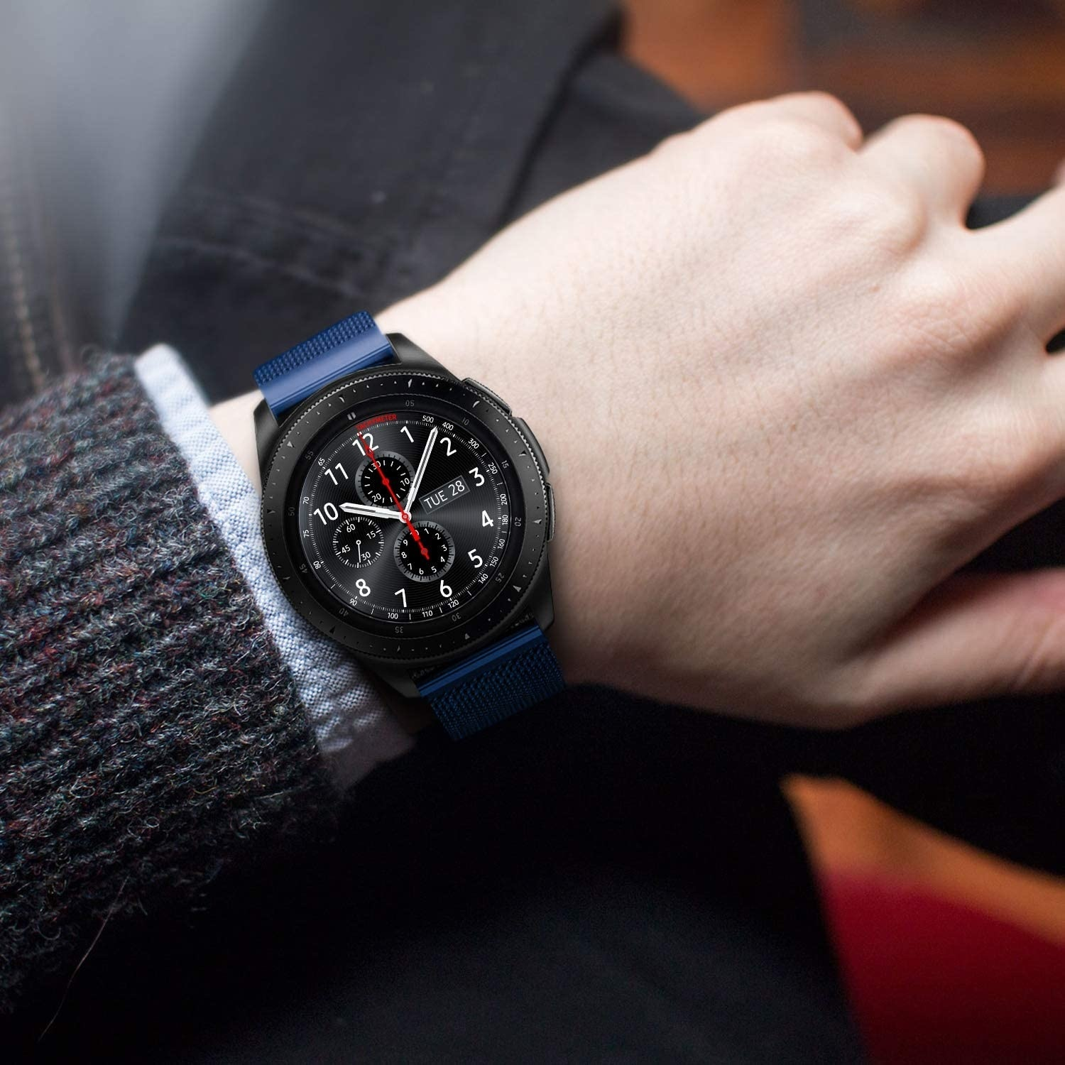 Eine Person trägt eine schwarze Smartwatch mit einem blauen Armband am Handgelenk, die ein stilvolles und funktionales Accessoire zeigt.