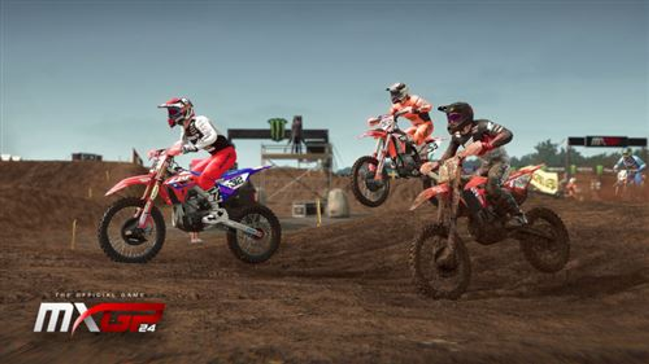 Scena di gioco di motocross con tre piloti su moto in aria, su pista sterrata.