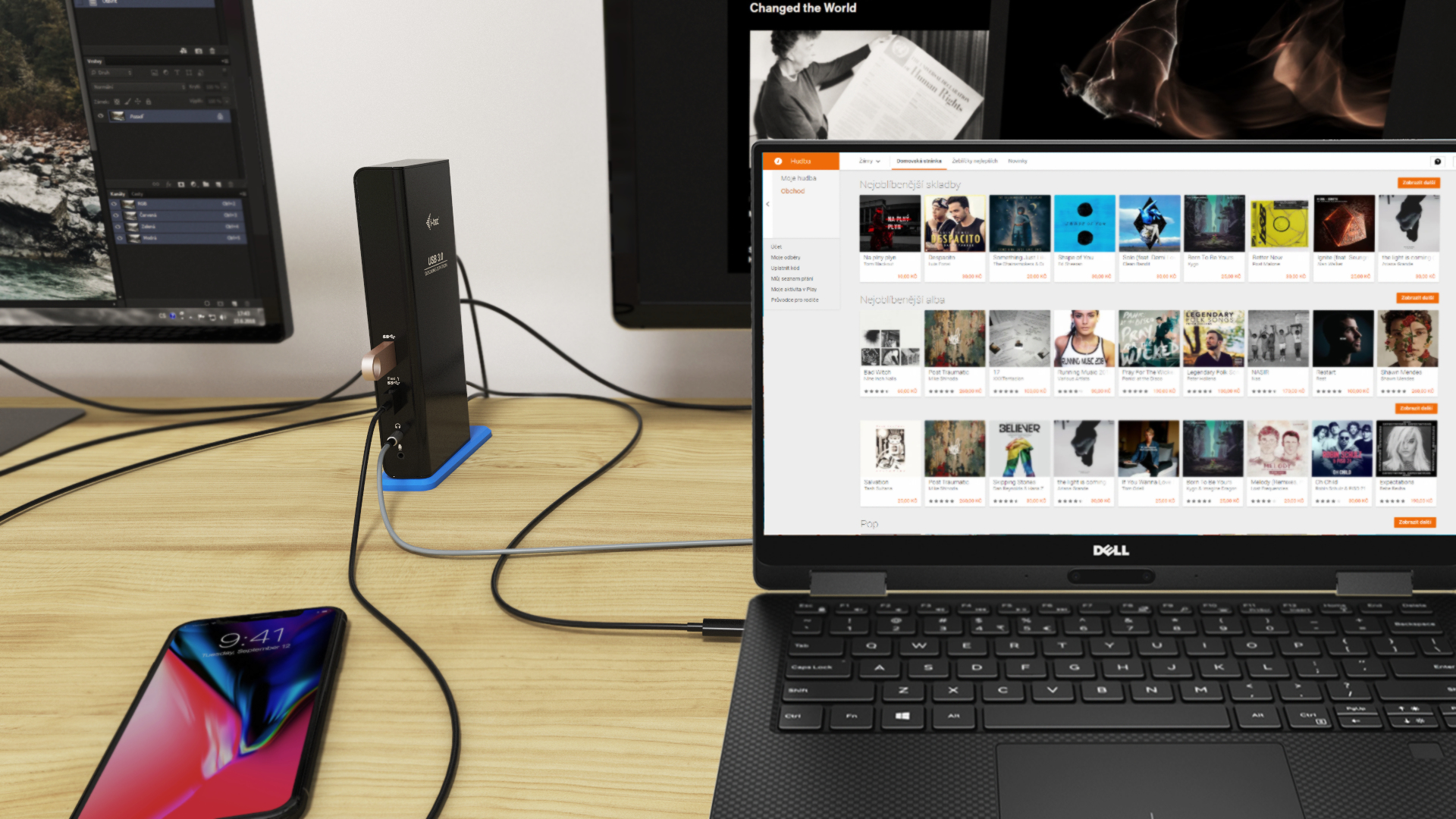Configurazione laptop, telefono e monitor con un hub nero collegato su una scrivania.