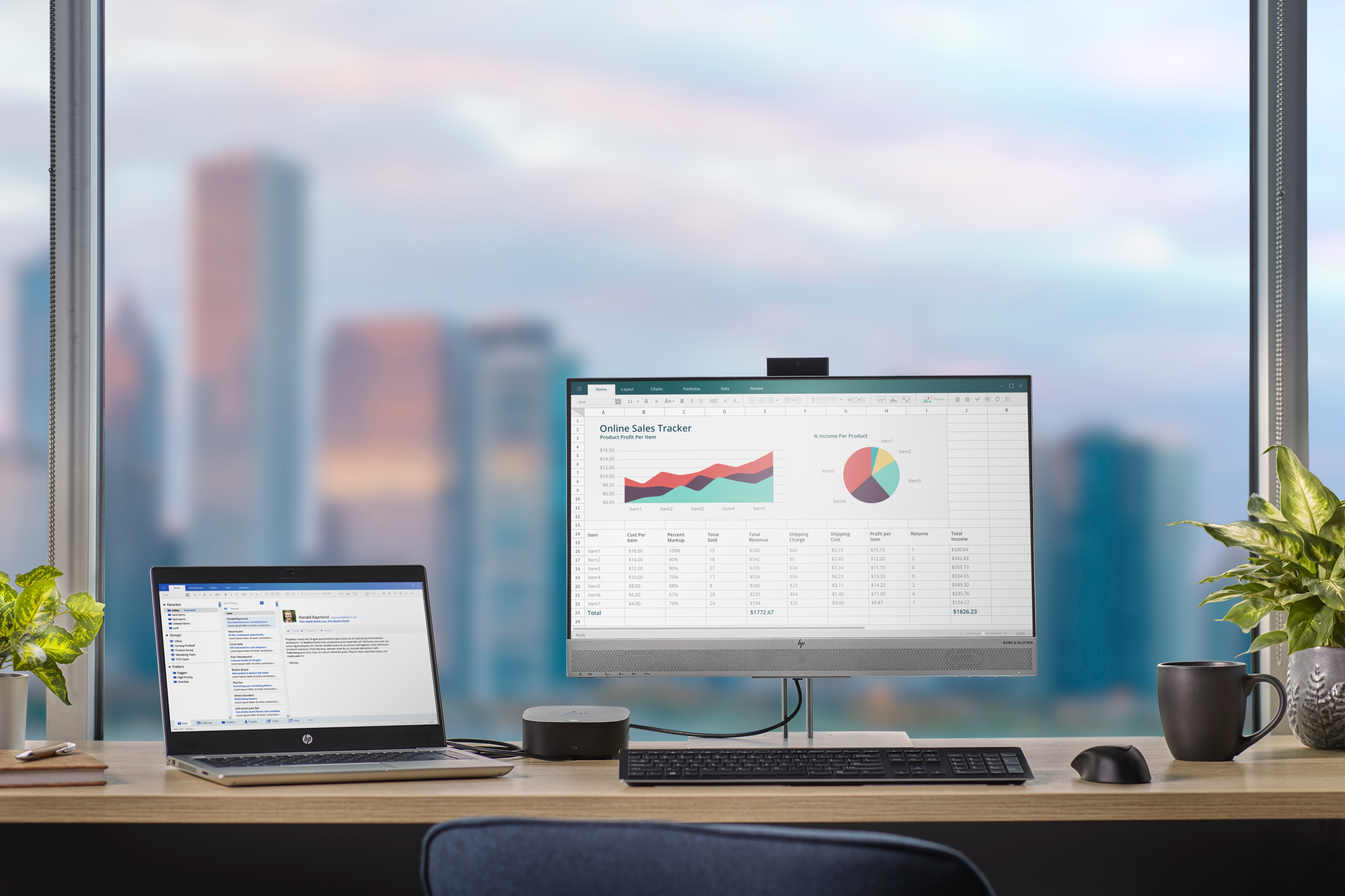 Un laptop e un monitor su una scrivania con un paesaggio urbano visibile sullo sfondo.