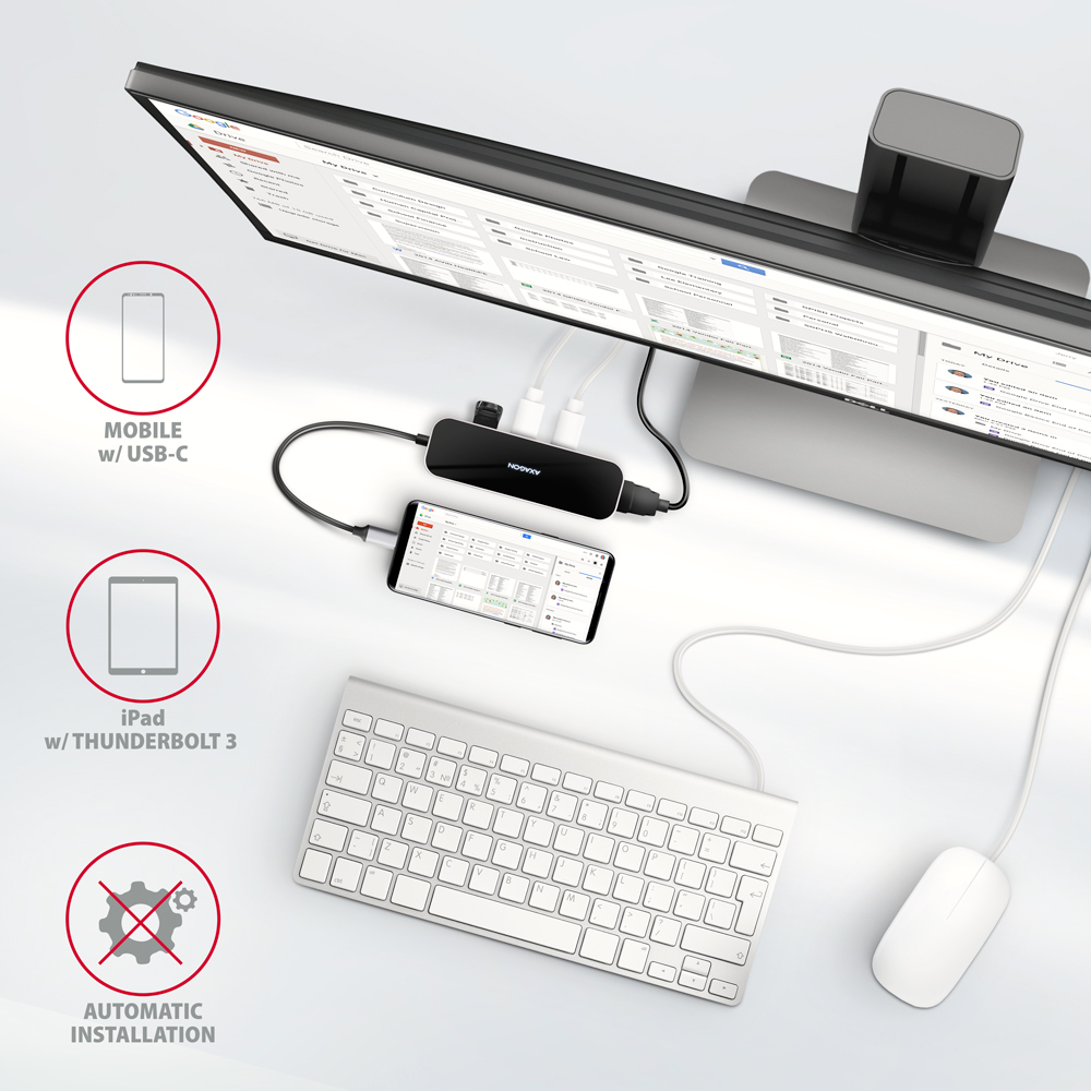 Un hub collega monitor, iPad e cellulare a tastiera e mouse bianchi.
