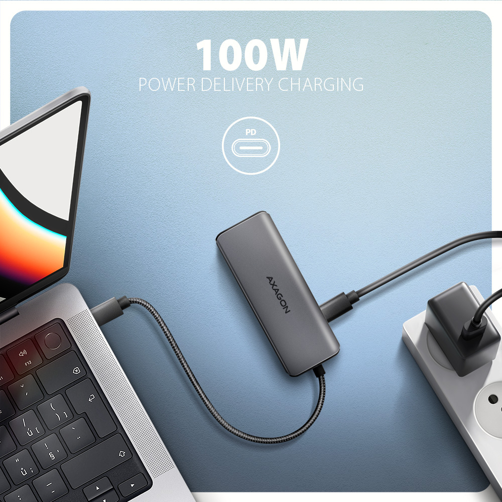 Laptop collegato a un hub per la ricarica a 100W. Hub e spina su superficie blu.