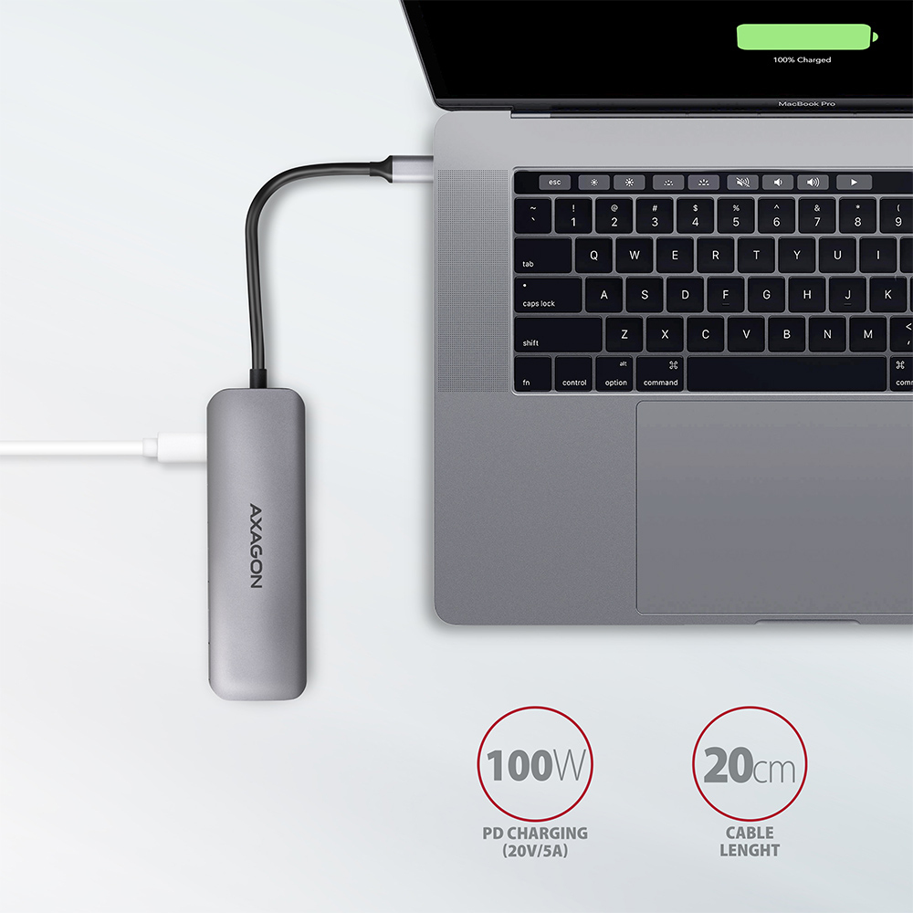 Laptop con hub USB grigio collegato, accanto a un cavo bianco e un'etichetta.