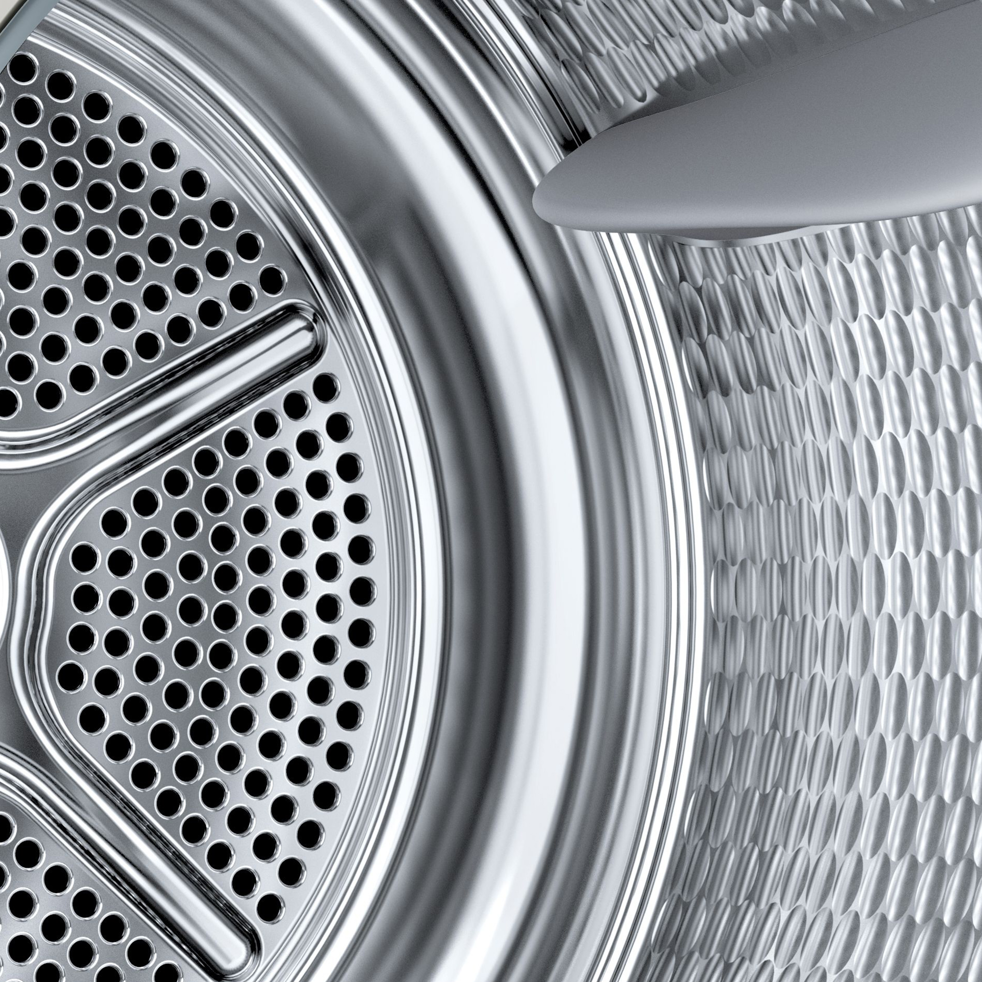 Primo piano dell'interno di un tamburo di essiccazione metallico con perforazioni e motivo circolare.