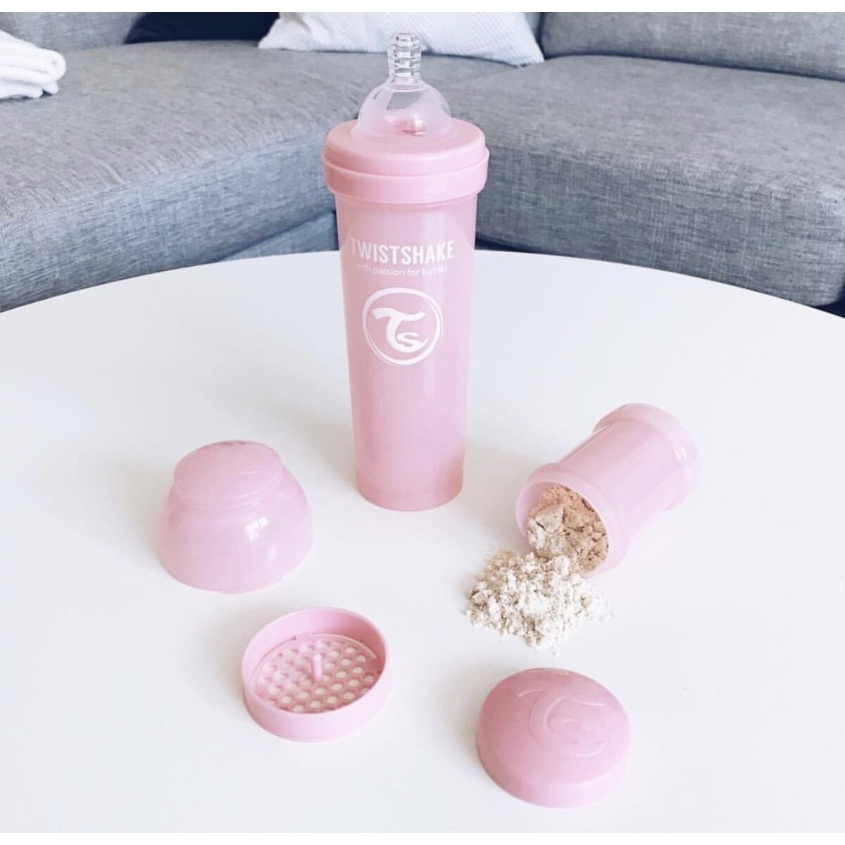 Ein rosa Babyflaschen-Set mit Pulver und anderen Komponenten. Es ist auf einer weißen Oberfläche.
