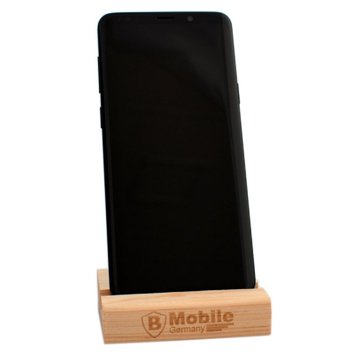 Ein schwarzes Smartphone steht in einem hölzernen Telefonständer. Der Ständer hat ein Logo.
