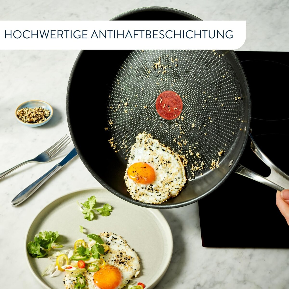 Pfanne mit Spiegelei und Teller mit ähnlichem Gericht. Die Pfanne hat einen roten Punkt in der Mitte.