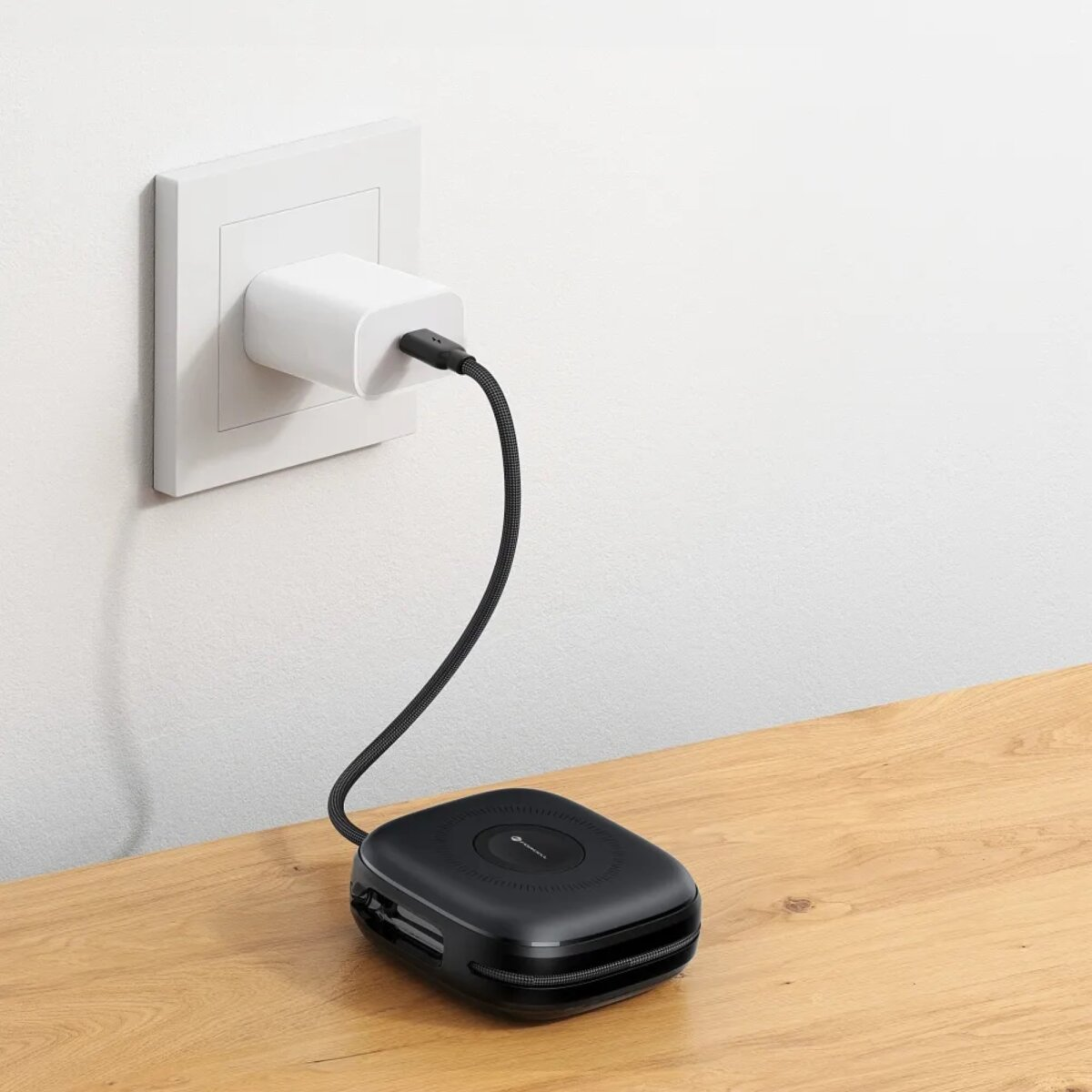 Ein schwarzes kabelloses Ladegerät, das mit einem weißen Wandstecker über ein USB-C-Kabel verbunden ist.