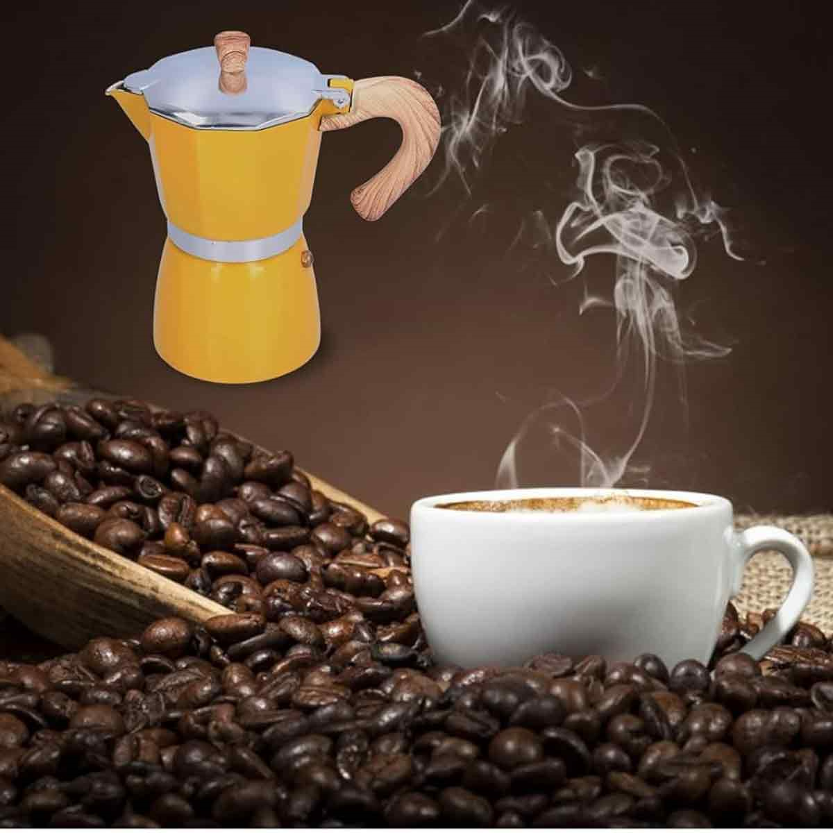 Gelbe Moka-Kanne mit Kaffeebohnen in einer Holzschaufel und eine Tasse Kaffee mit Dampf.