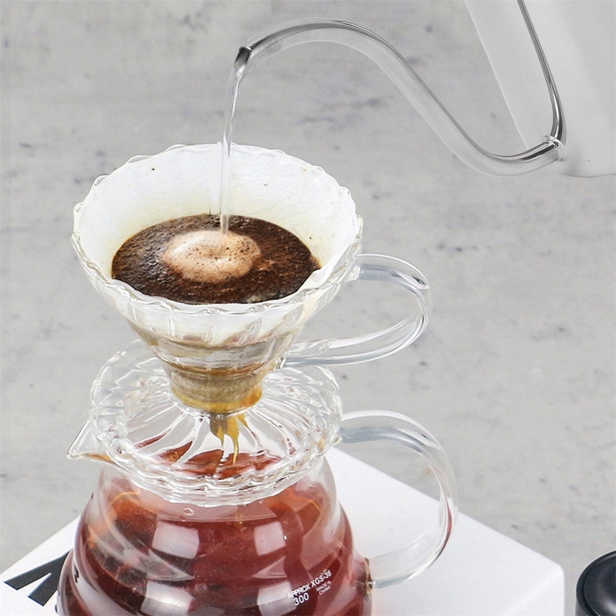 Pour-over Kaffeezubereitung. Heißes Wasser gießt in einen Filter, Kaffeepulver und tropft in eine Glaskaraffe.