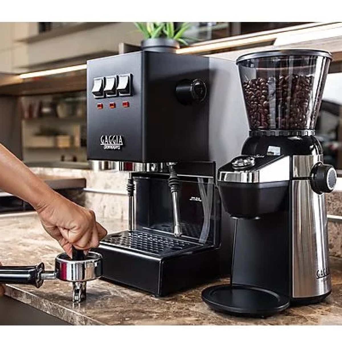 Ekspres do kawy i młynek na blacie kuchennym. Ręka używa ubijaka.