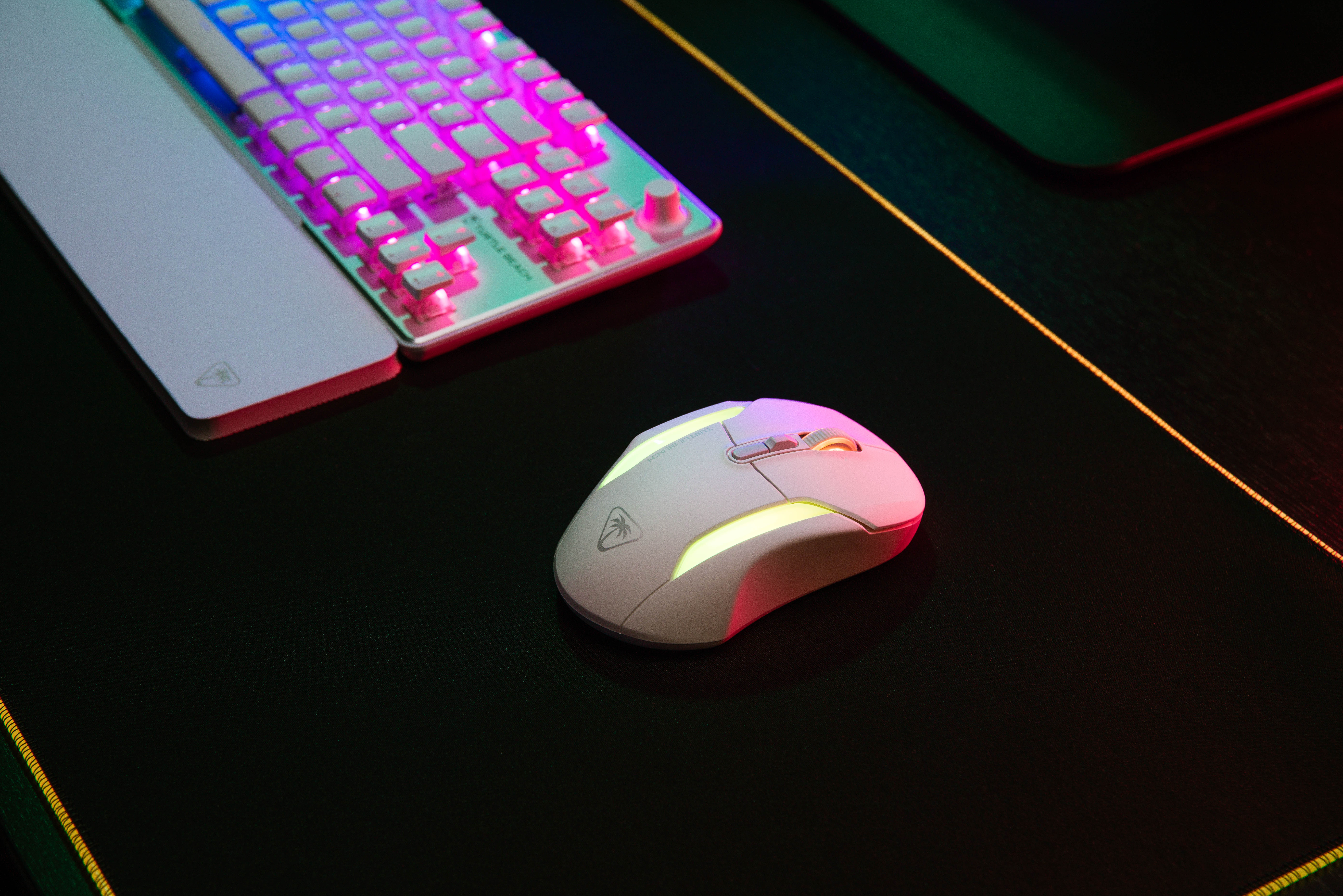 Biała mysz i klawiatura gamingowa na czarnej podkładce, z podświetleniem.