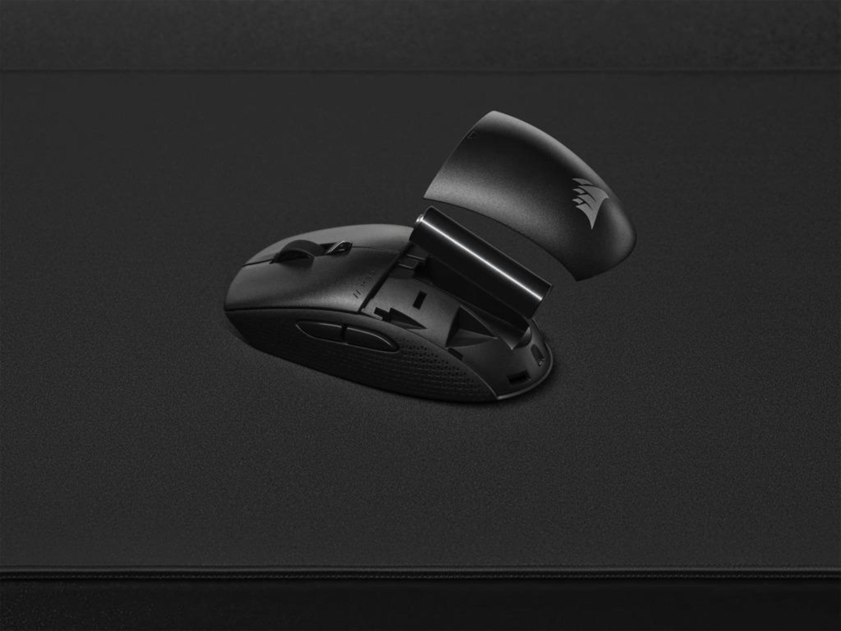 Czarna mysz z otwartym tyłem i baterią na czarnej powierzchni. Widok perspektywiczny.