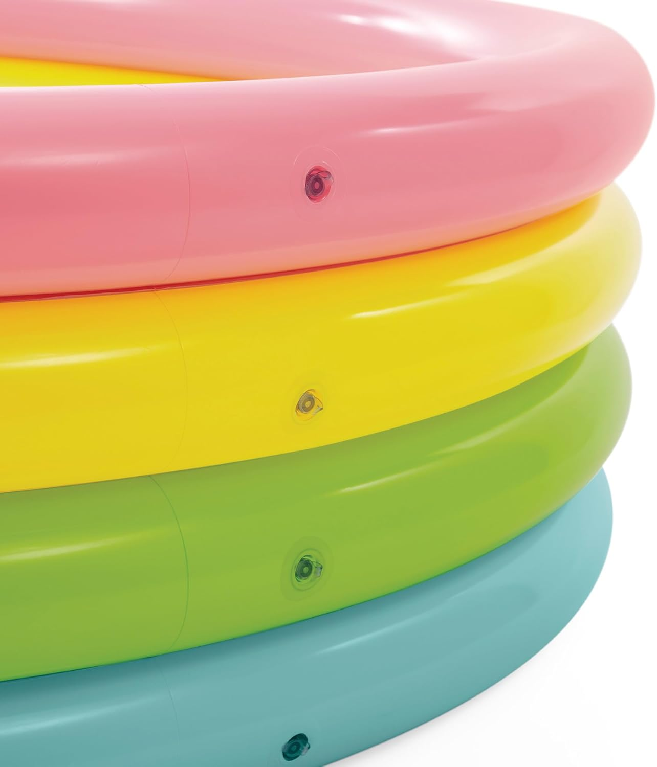Zbliżenie na dmuchany basen. Basen składa się z czterech kolorowych pierścieni: różowego, żółtego, zielonego i niebieskiego.