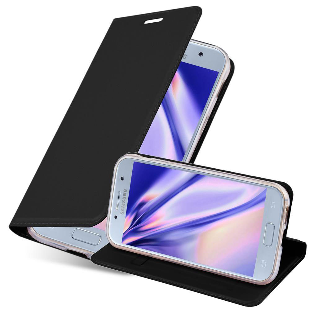 Un teléfono negro está en una funda negra. La funda está abierta y el teléfono visible. Un segundo teléfono está en el fondo.