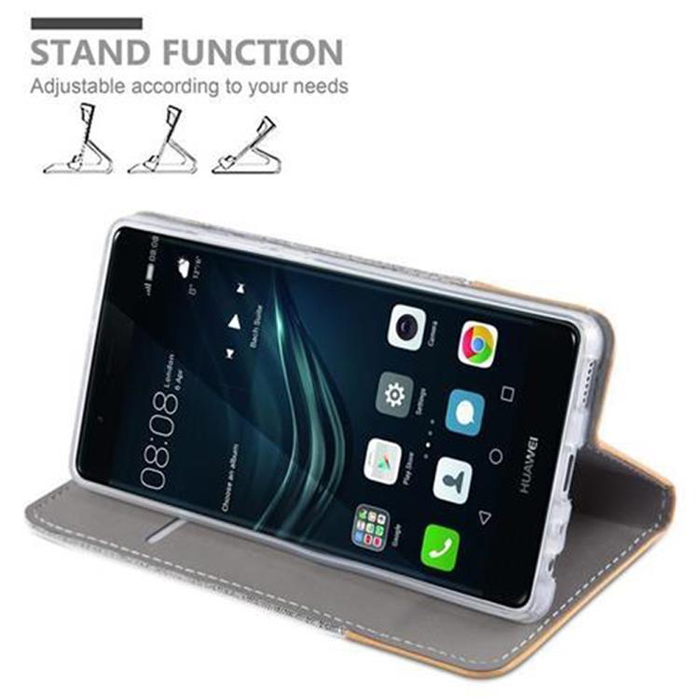 Smartphone in einer Hülle, aufgestellt. Der Bildschirm zeigt die Uhrzeit mit grauem Hintergrund.