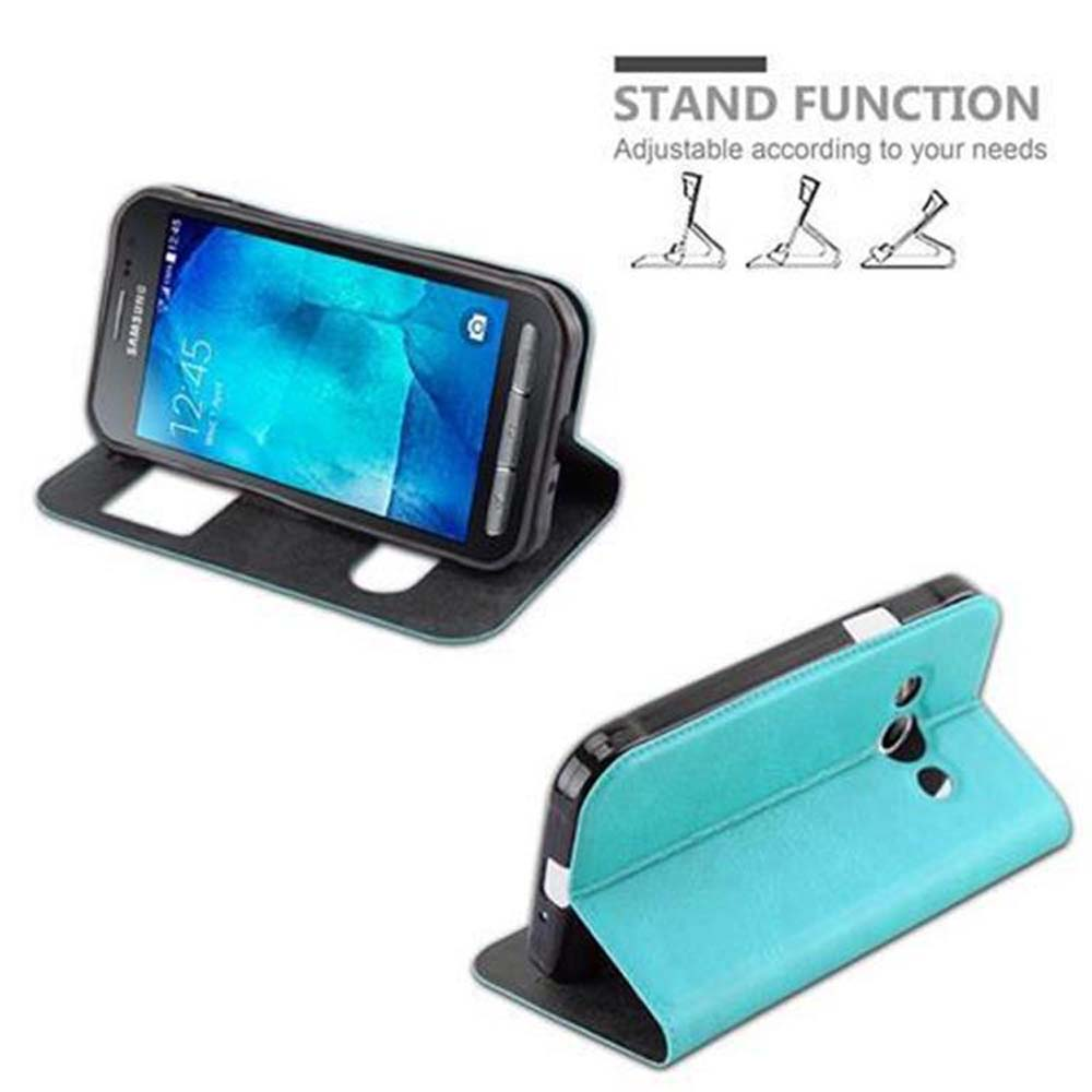 Un telefono in funzione stand con una custodia blu. Lo schermo del telefono mostra un orologio. C'è un'icona della funzione stand.