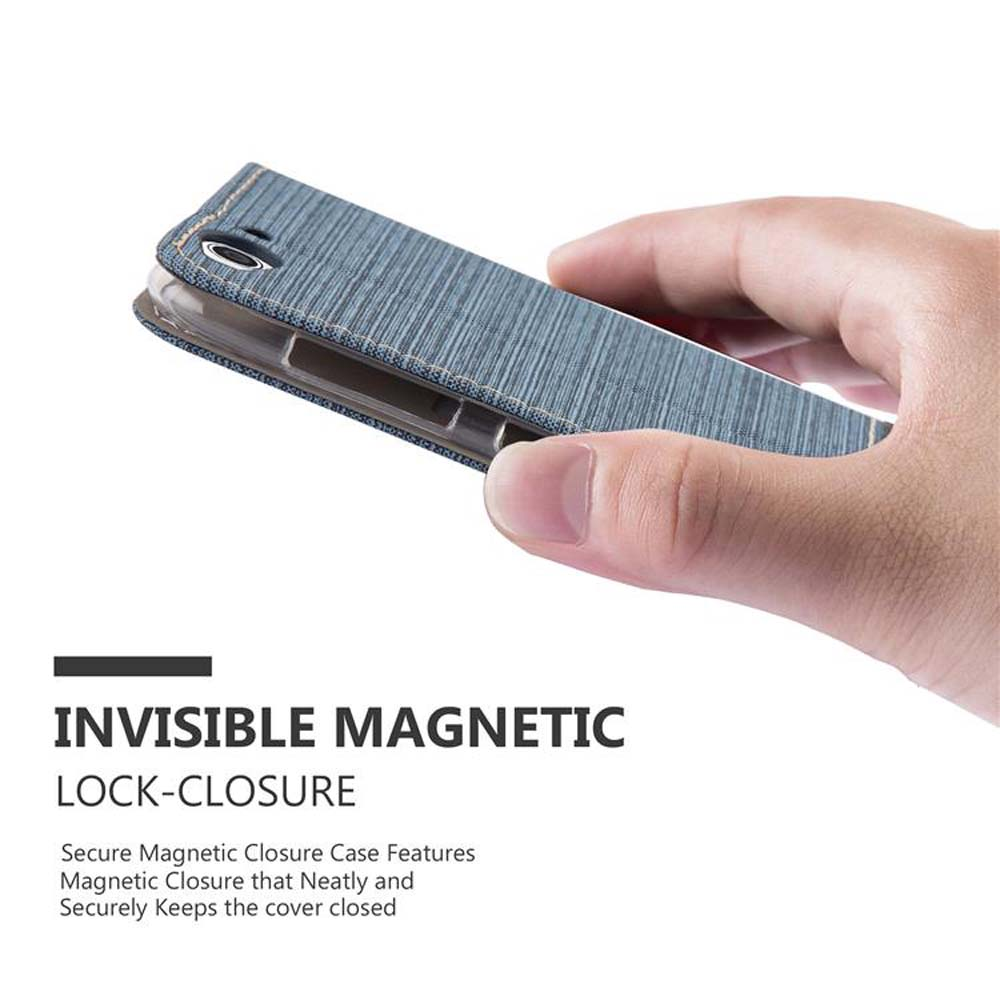 Una mano che tiene una custodia per telefono chiusa in tessuto blu, con testo sulla chiusura magnetica.