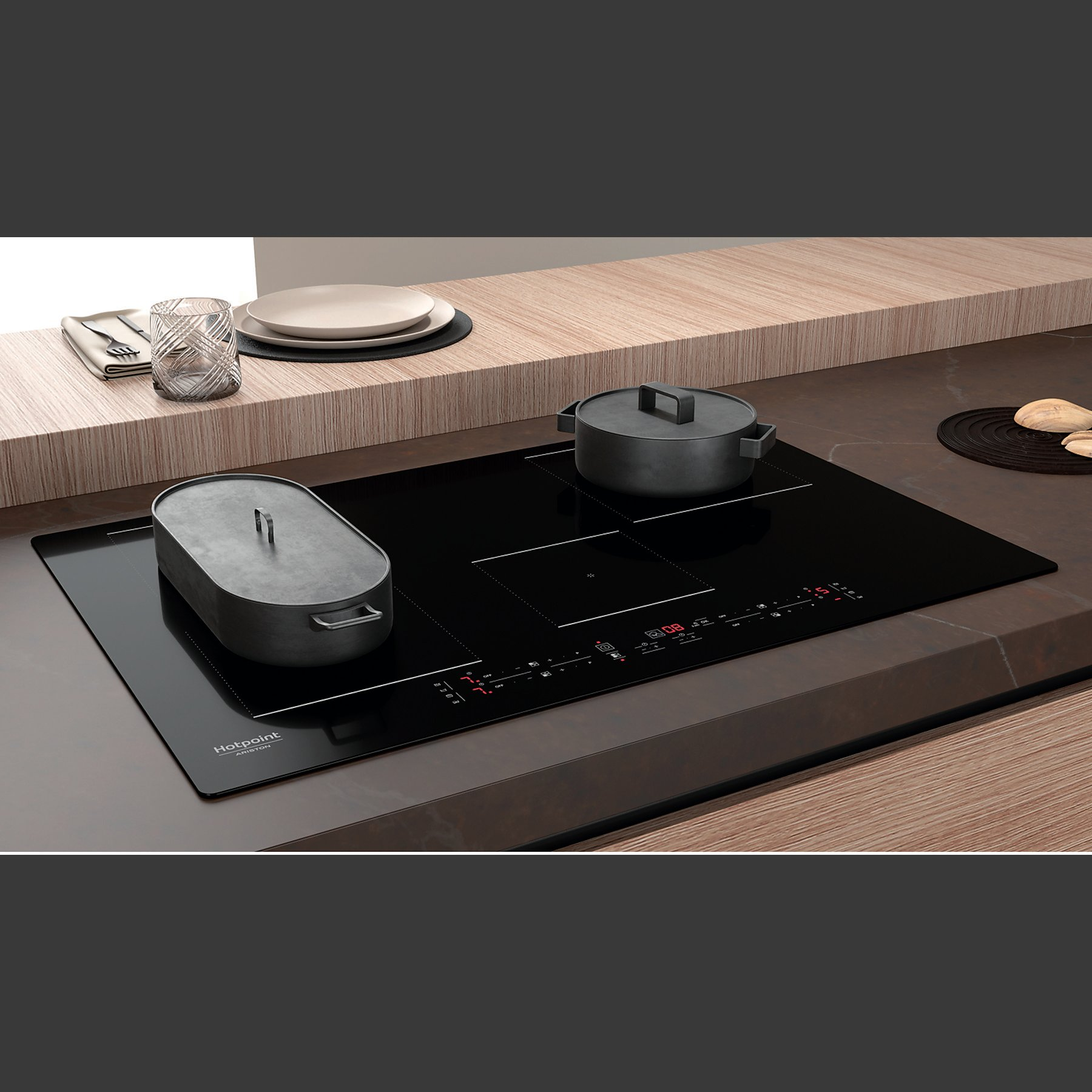 Czarna płyta indukcyjna Hotpoint z czarnymi garnkami.