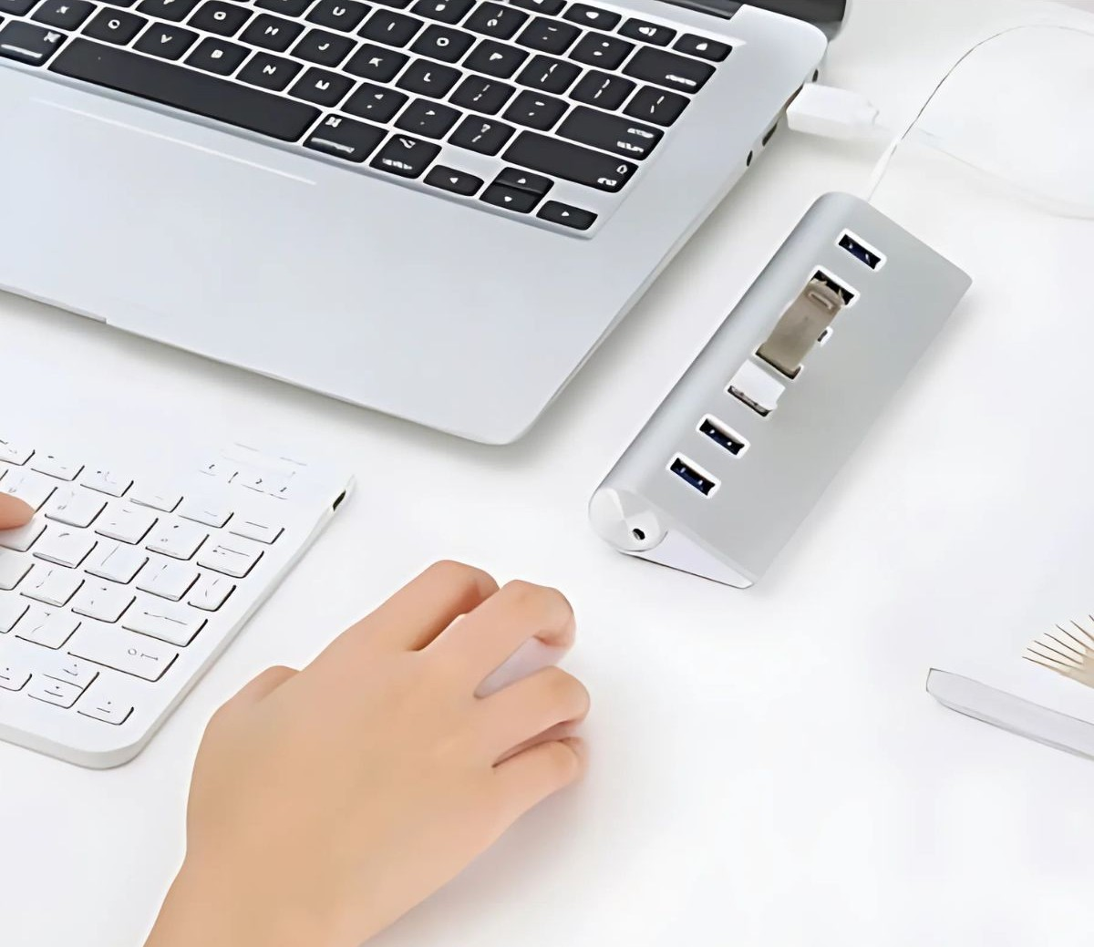 Konfiguracja biurka: dłonie używają myszy i klawiatury z koncentratorem USB i laptopem.