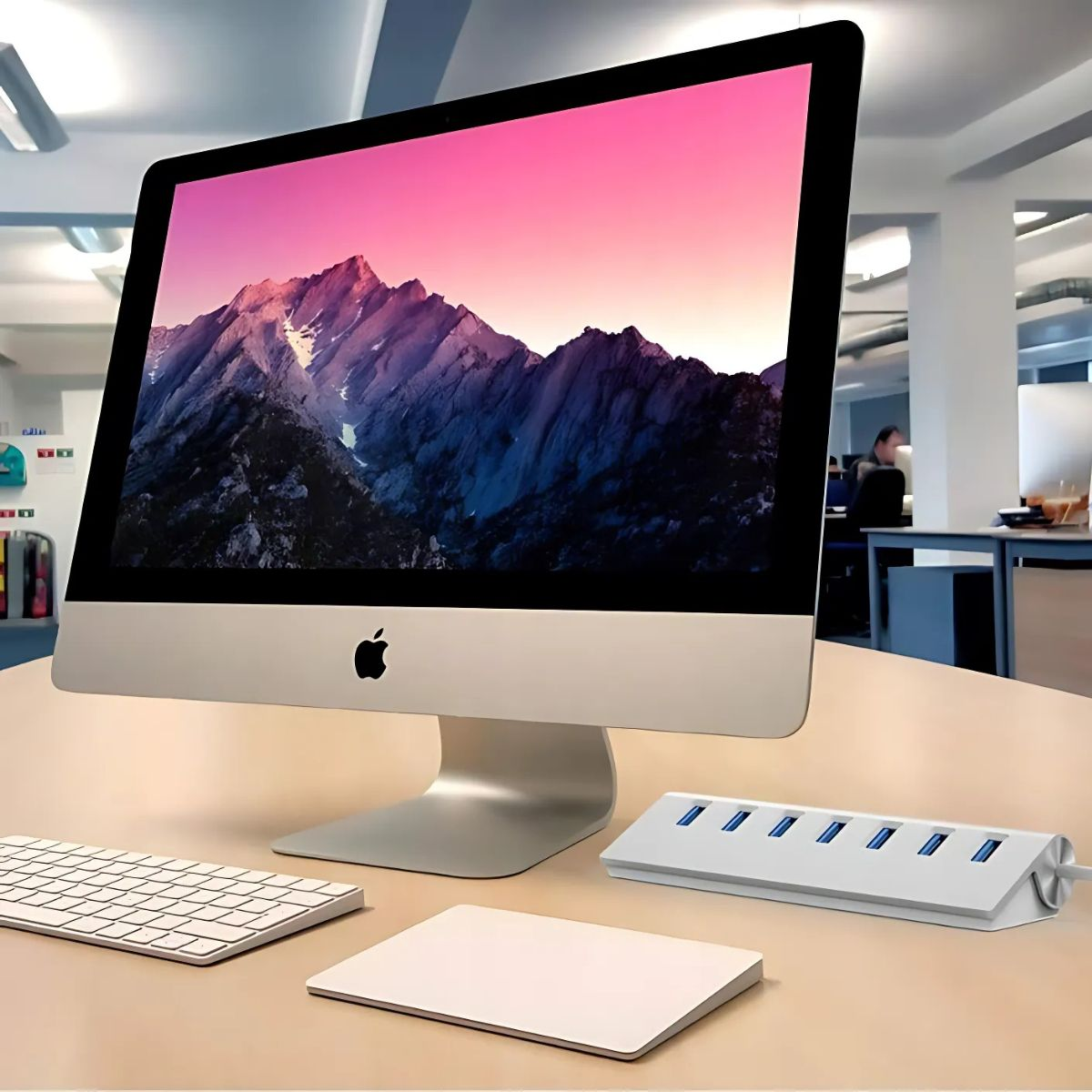 Konfiguracja komputera Apple na stole. Zawiera monitor, klawiaturę, mysz i koncentrator USB.