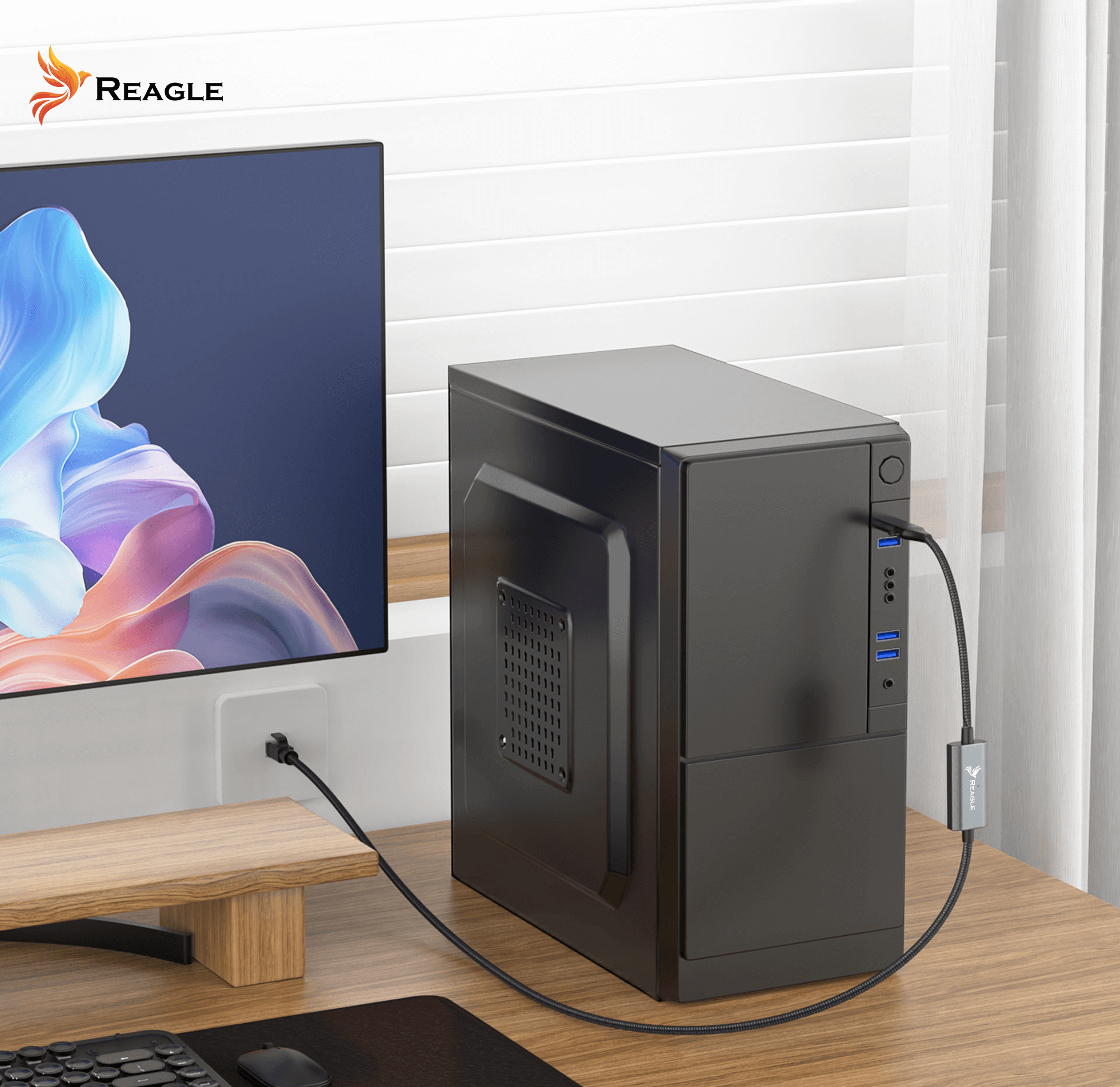 Konfiguracja komputera z czarną obudową, monitorem, biurkiem i kablem. Widoczna marka Reagle.