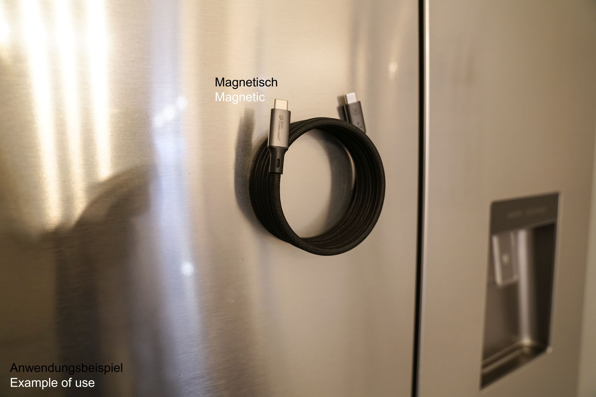 Ein schwarzes Ladekabel ist magnetisch an einer silbernen Kühlschranktür befestigt.