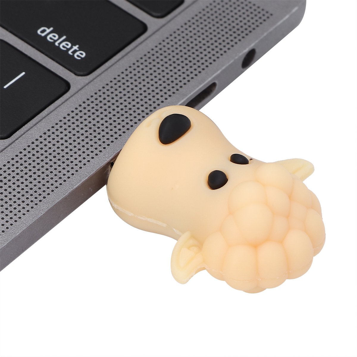 Ein beigefarbener USB-Stick in Schaf-Form ist an die Tastatur eines Laptops angeschlossen.