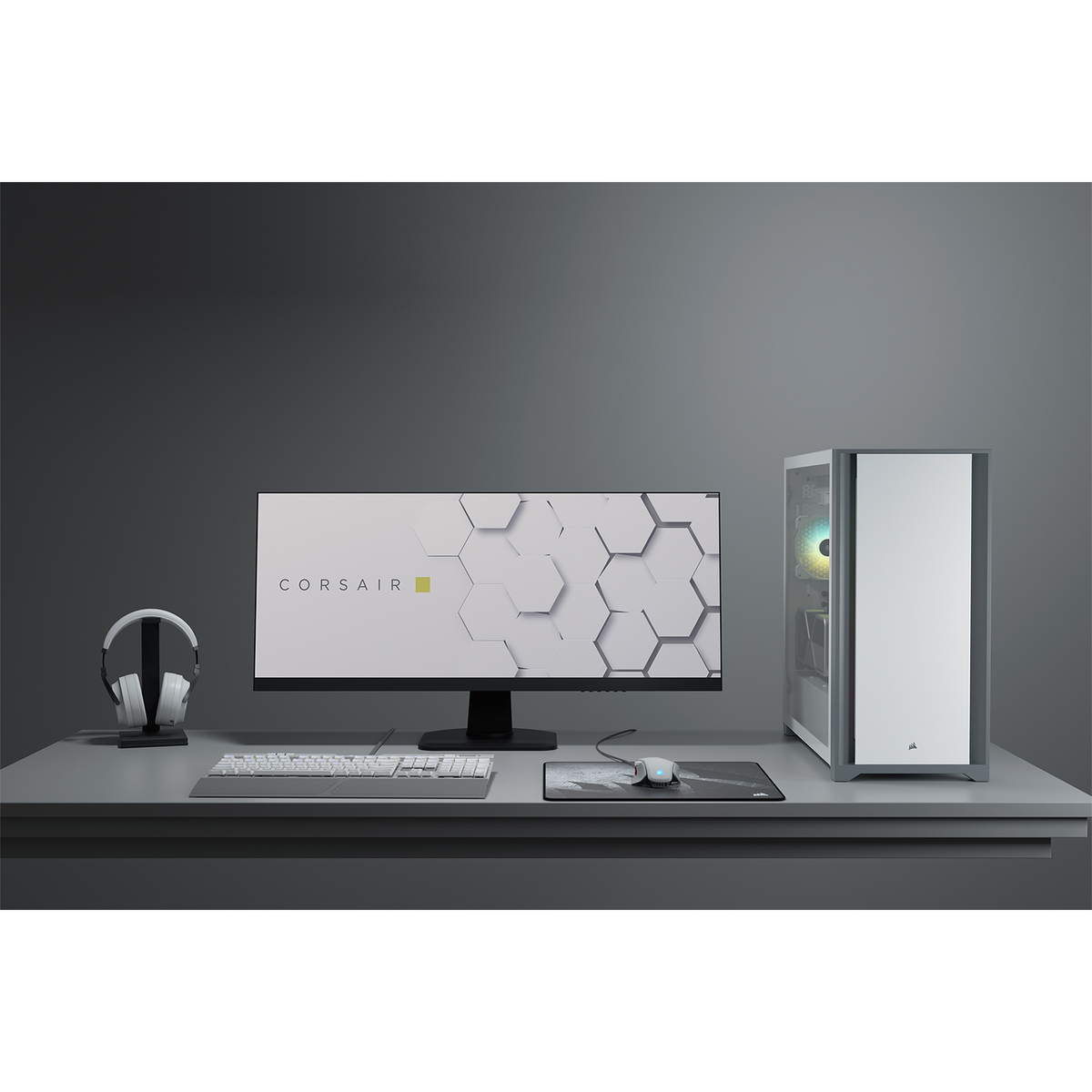 Una scrivania con computer, monitor, tastiera, mouse e cuffie. Schema di colori bianco e grigio.