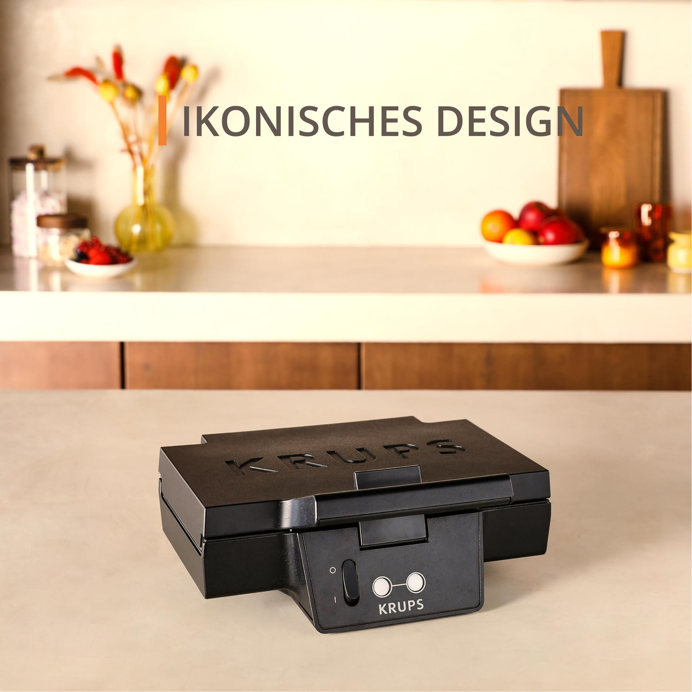 Czarny gofrownica KRUPS na białym blacie. Obrazek ma tekst: kultowy design. Tło jest rozmyte.