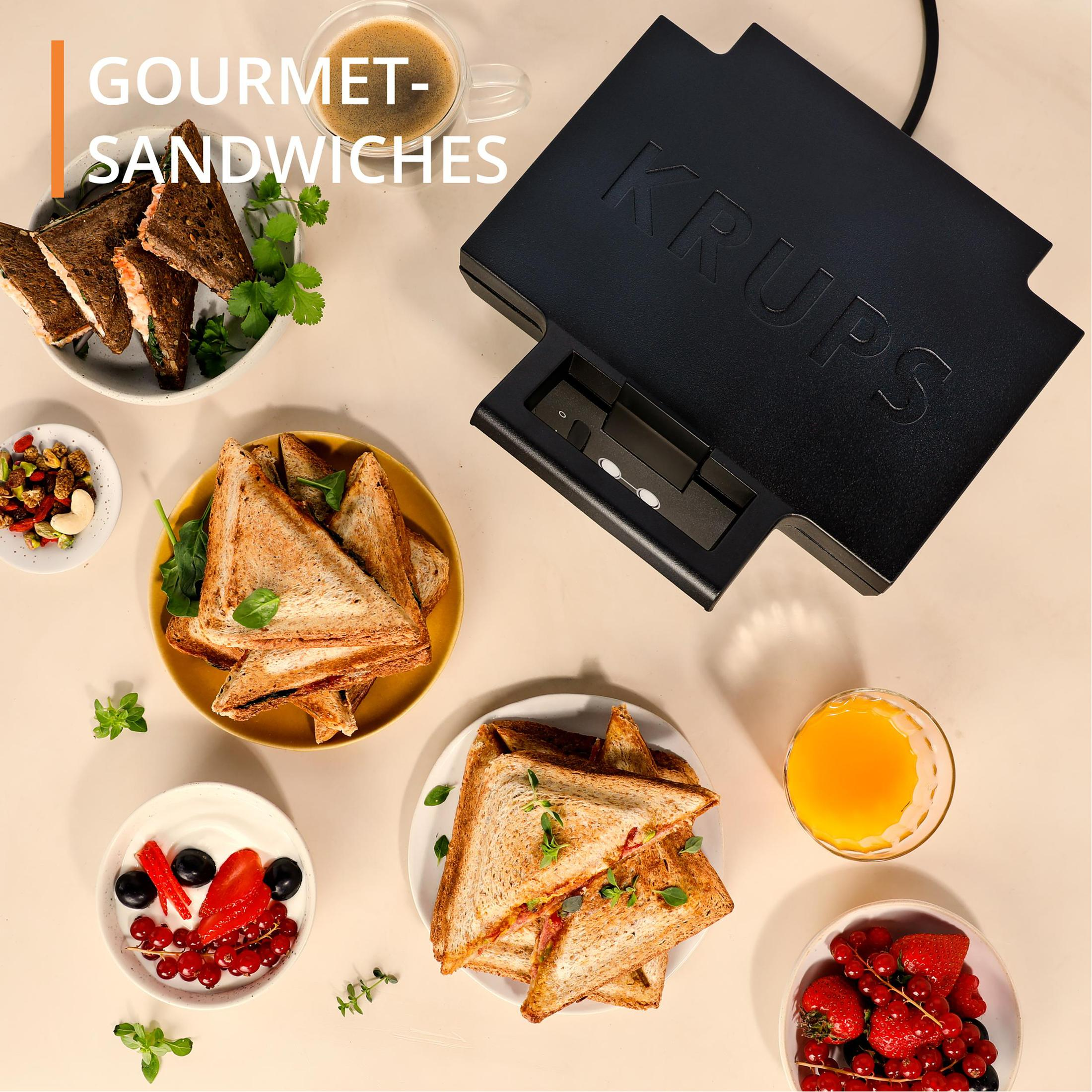 Kanapki gourmet na talerzach z kawą i sokiem pomarańczowym, na stole.