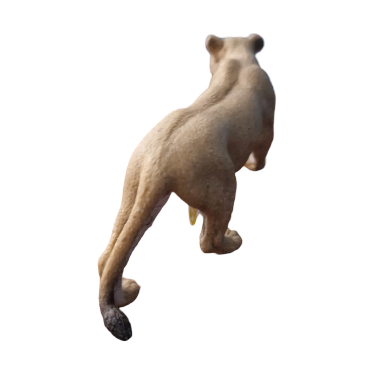 Una statuetta di leonessa vista da dietro. La leonessa è in posizione di camminata ed è color tan.