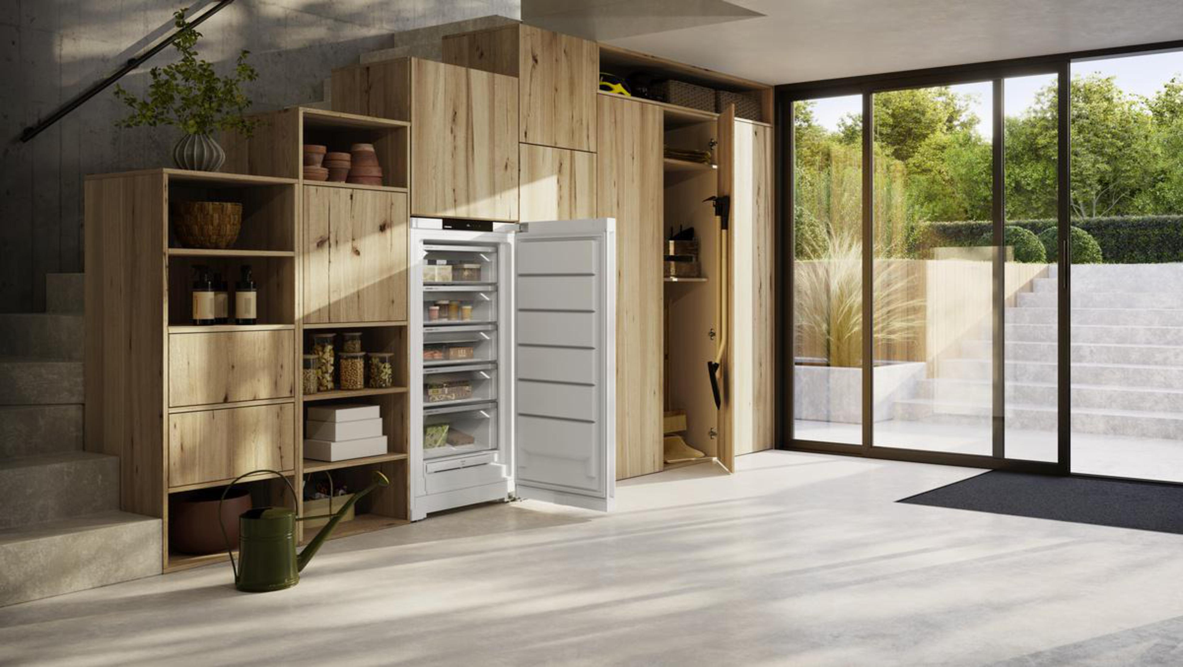 Ein modernes Interieur mit Holzschränken, einem Gefrierschrank und einer Treppe zur Tür.