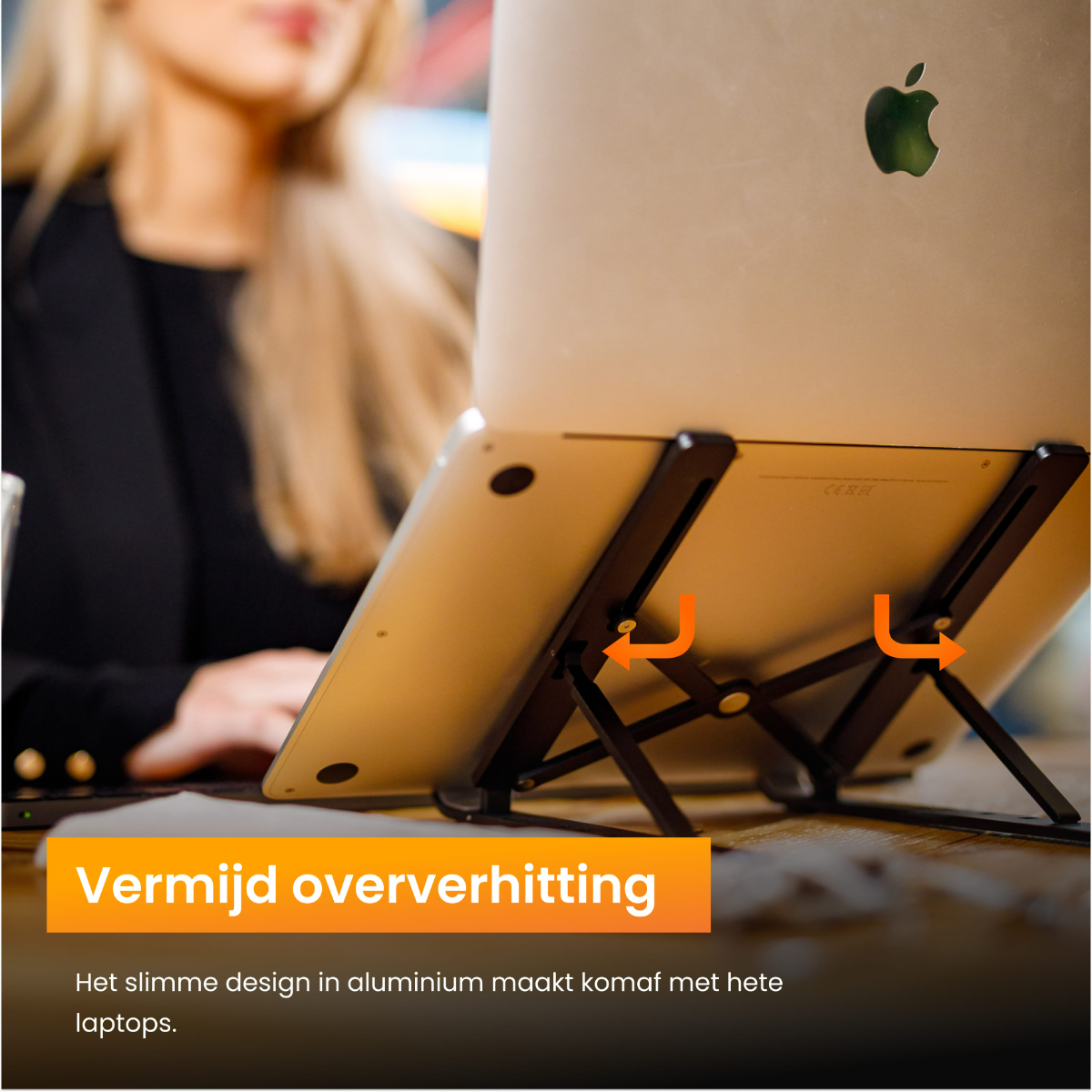 Laptop op een standaard. De wazige afbeelding van een vrouw staat op de achtergrond. Standaard heeft oranje tekst.