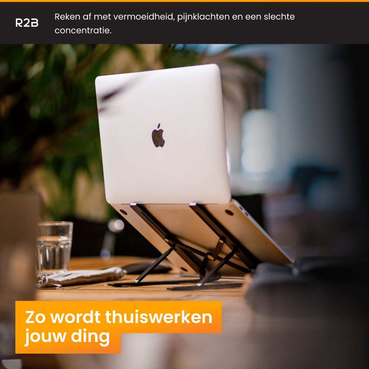 Laptop op een standaard, glas water op de tafel.