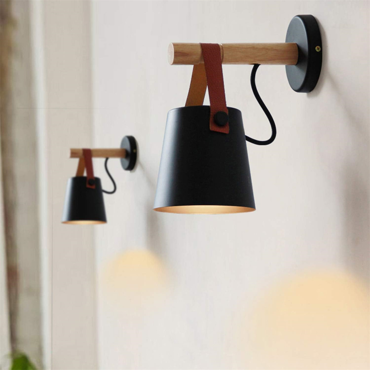 Zwei schwarze Wandlampen mit Holmen und Lederriemen.