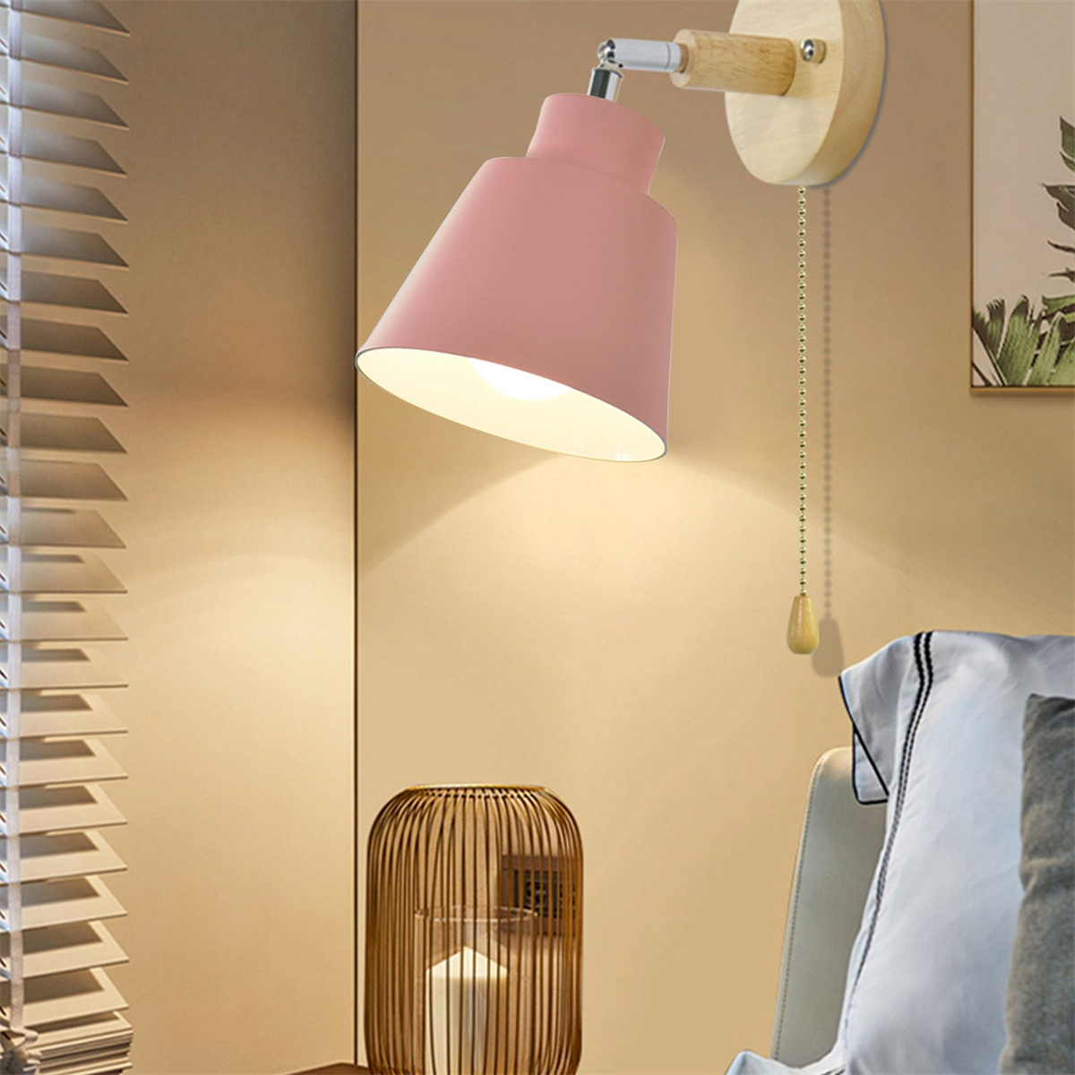 Pinke Wandlampe mit Holzsockel und Zugkordel. Die Lampe ist auf ein Bett ausgerichtet.